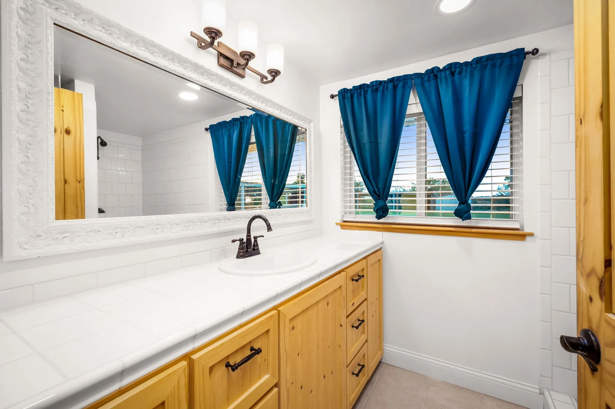 Bathroom vanity featuring light wood cabinetry, a white countertop, and an integrated white sink