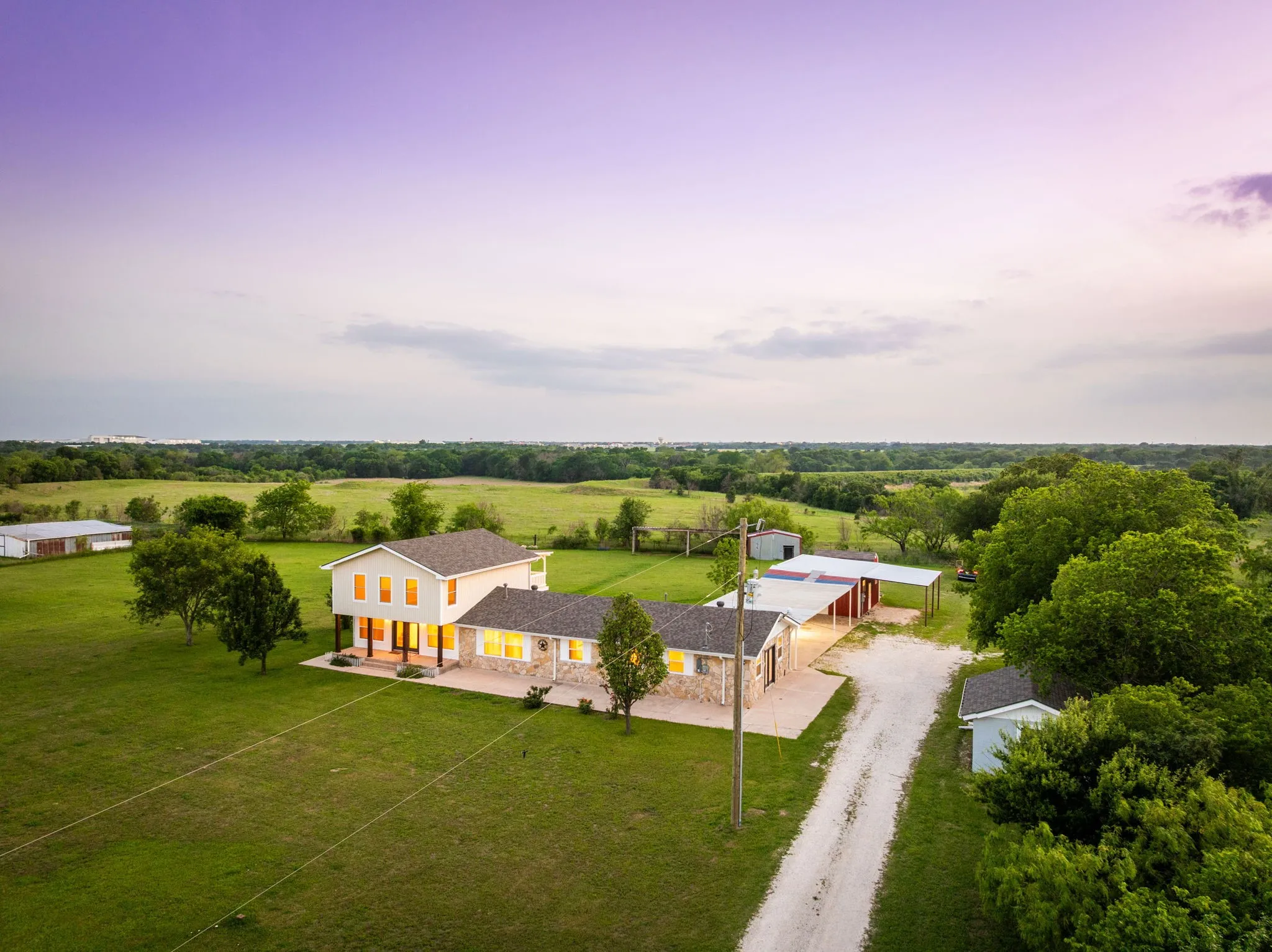 Expansive property featuring a multi-level residence with stone and siding exterior, a separate outbuilding, and a covered shed structure