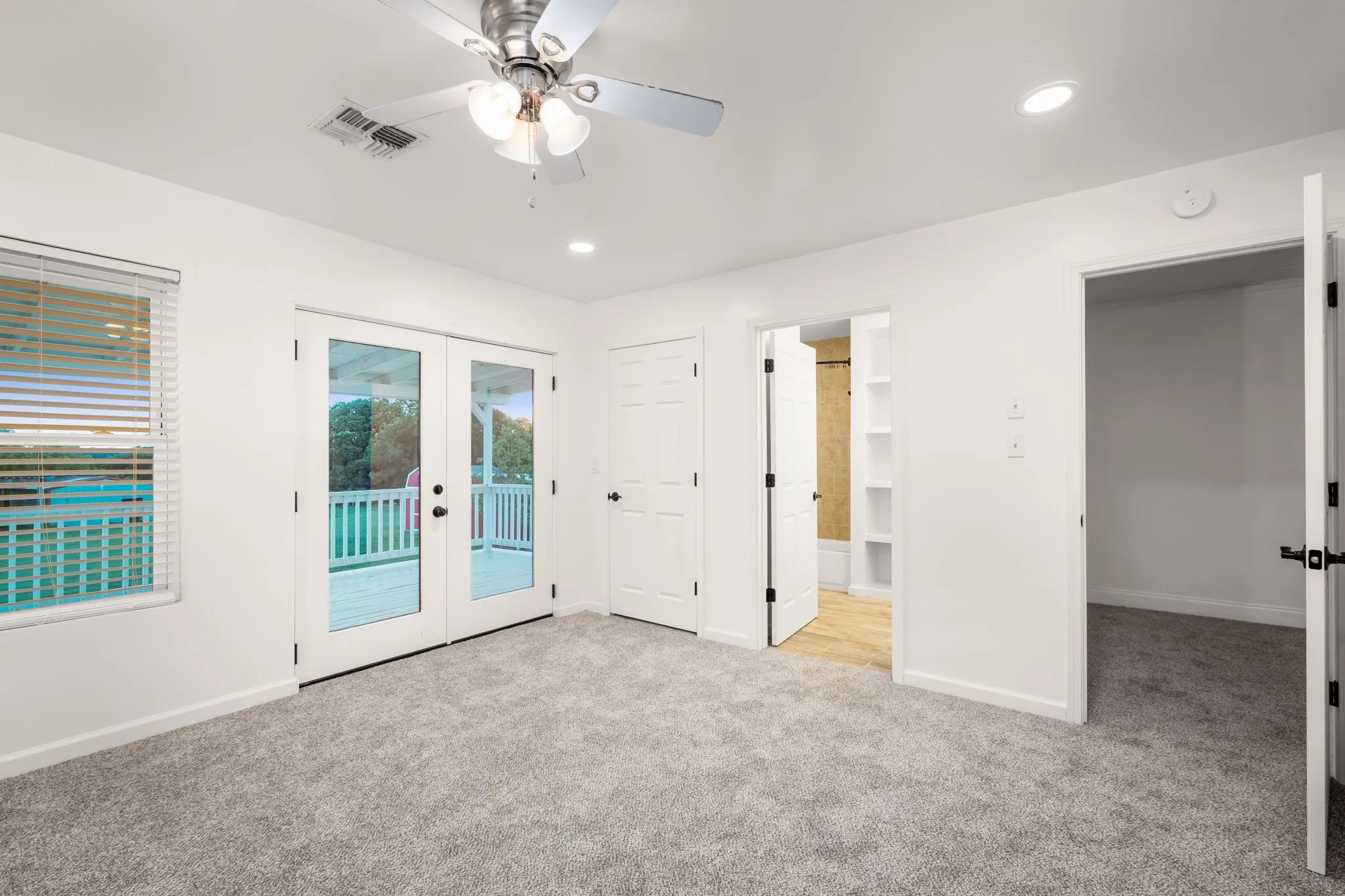 Spacious room featuring light gray carpet flooring, recessed lighting, and a ceiling fan