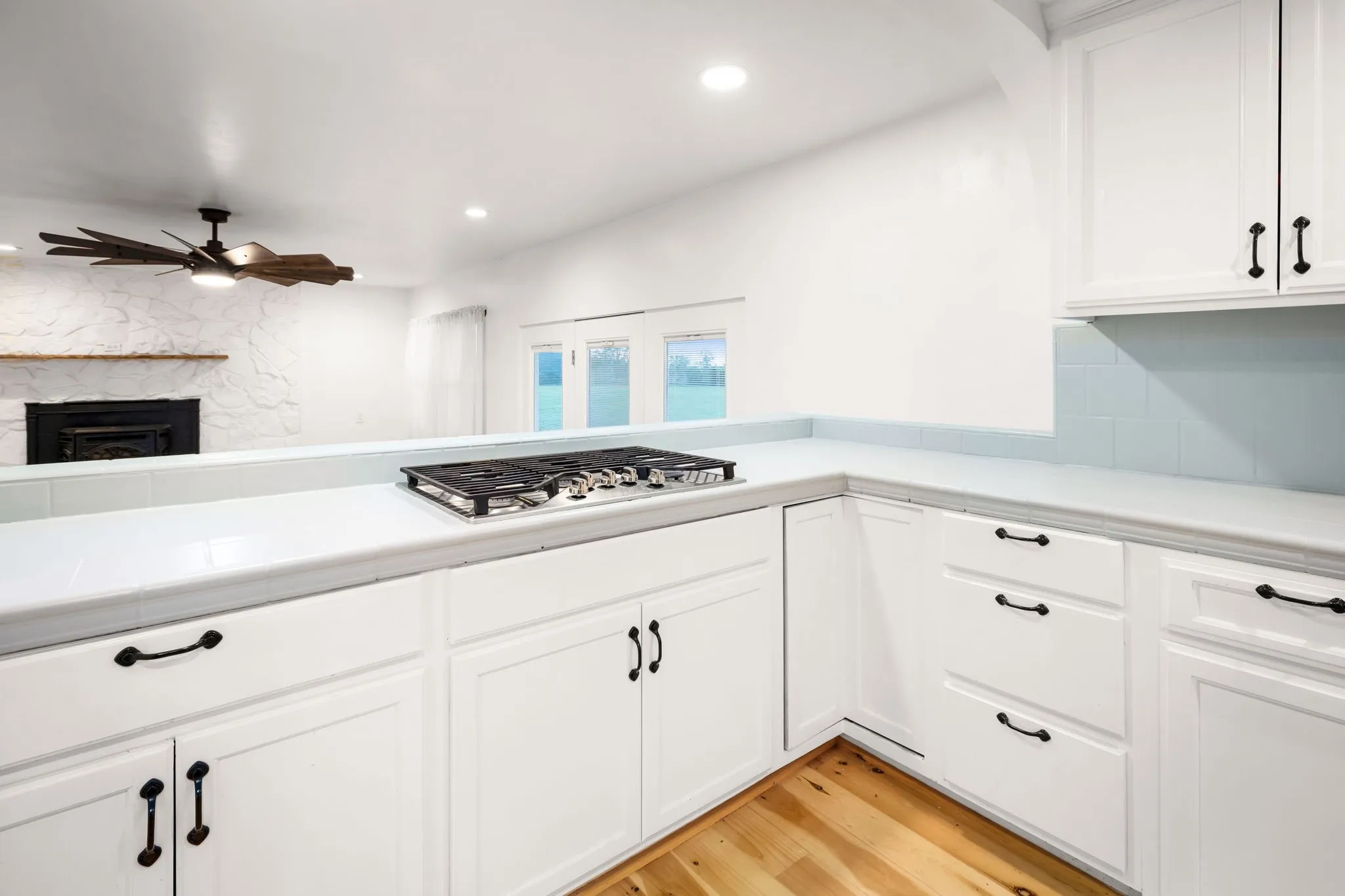 Kitchen featuring white cabinetry with dark hardware, a built-in gas cooktop, light countertops, and a subway tile backsplash