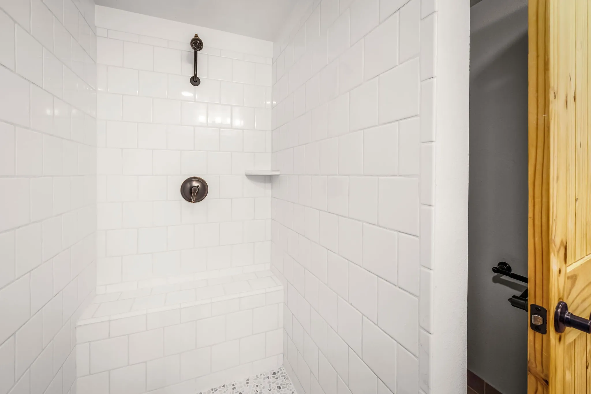 Shower with white subway tile, built-in bench, bronze-finish fixtures, and a recessed niche