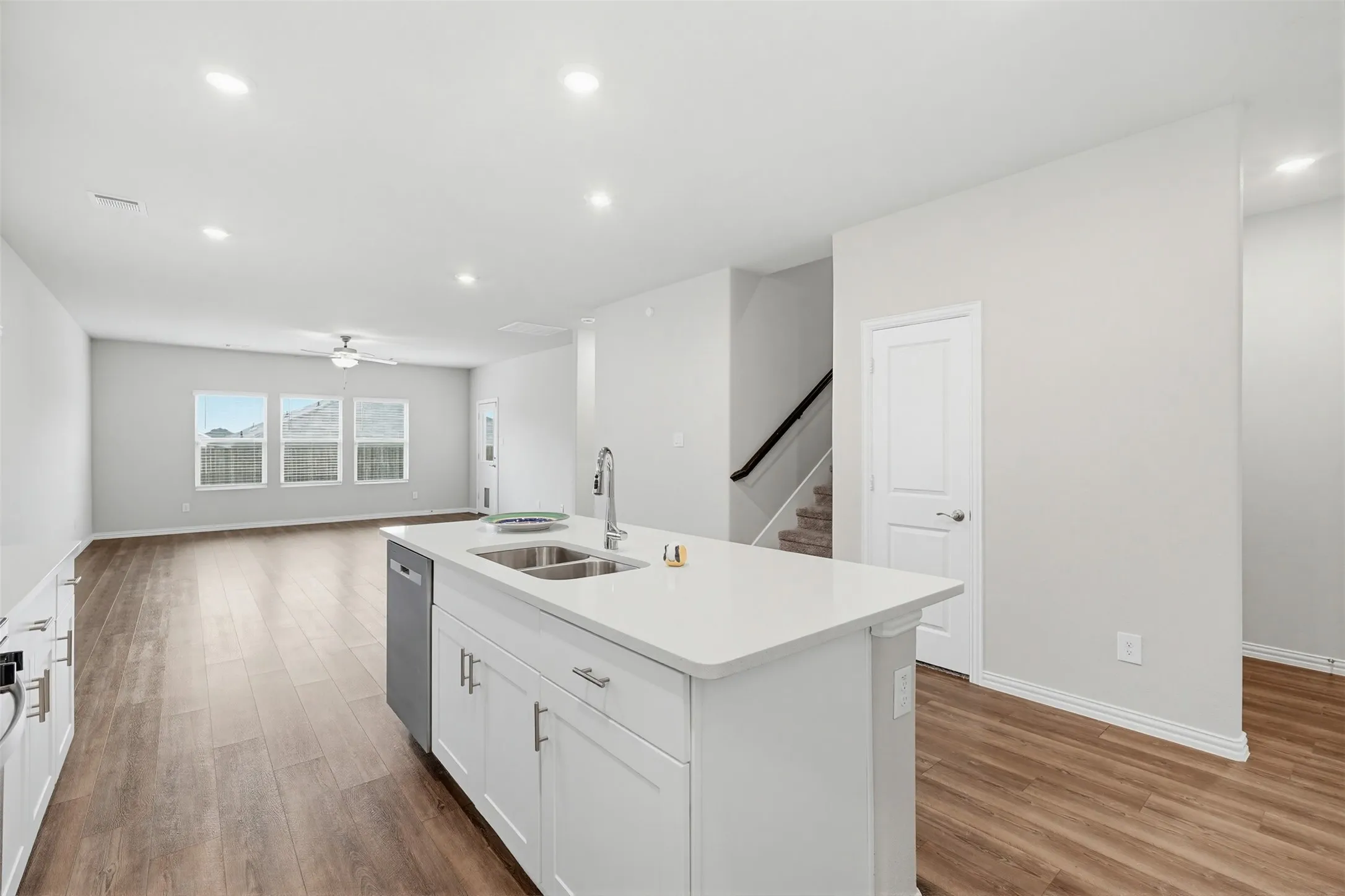 Kitchen island with an undermount double basin sink, stainless steel faucet, and white cabinetry