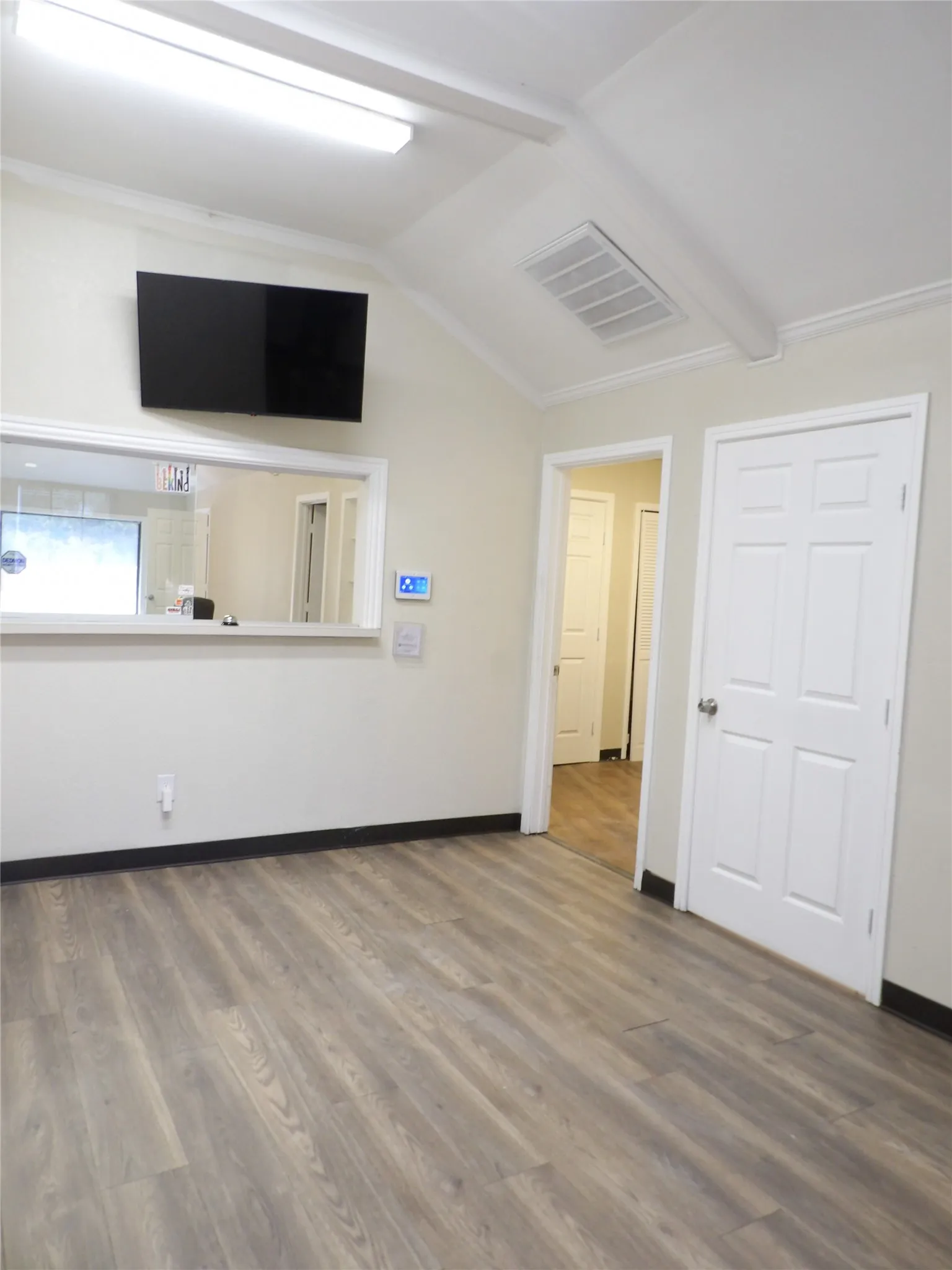 Spacious interior reception room featuring wood-finish flooring, vaulted ceiling, and recessed lighting