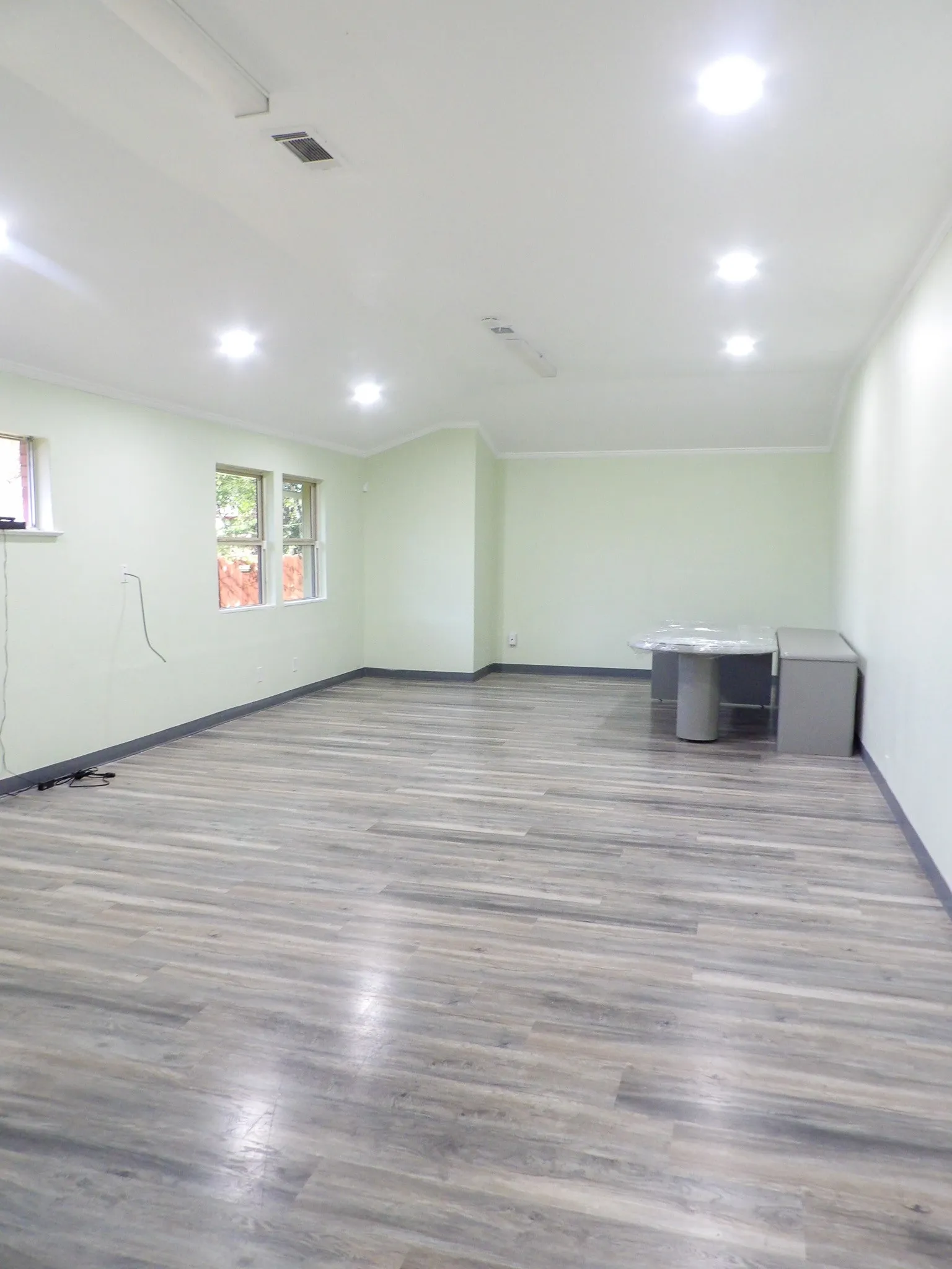 Spacious Conference room featuring wide plank wood-finish flooring, recessed lighting, crown molding, and multiple windows