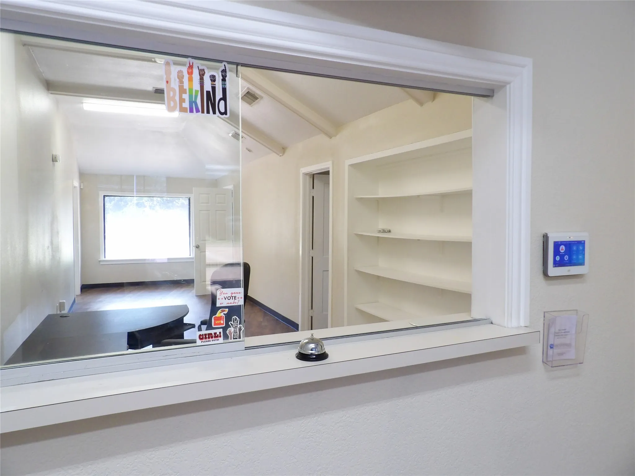Reception counter with a pass-through window, built-in shelving, and a modern wall-mounted control panel