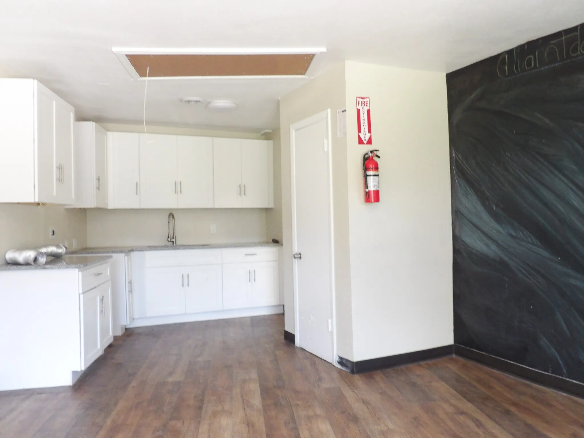 Kitchenette featuring white cabinetry, light-colored countertops, a single basin sink with a high-arc faucet, and wood-finish flooring