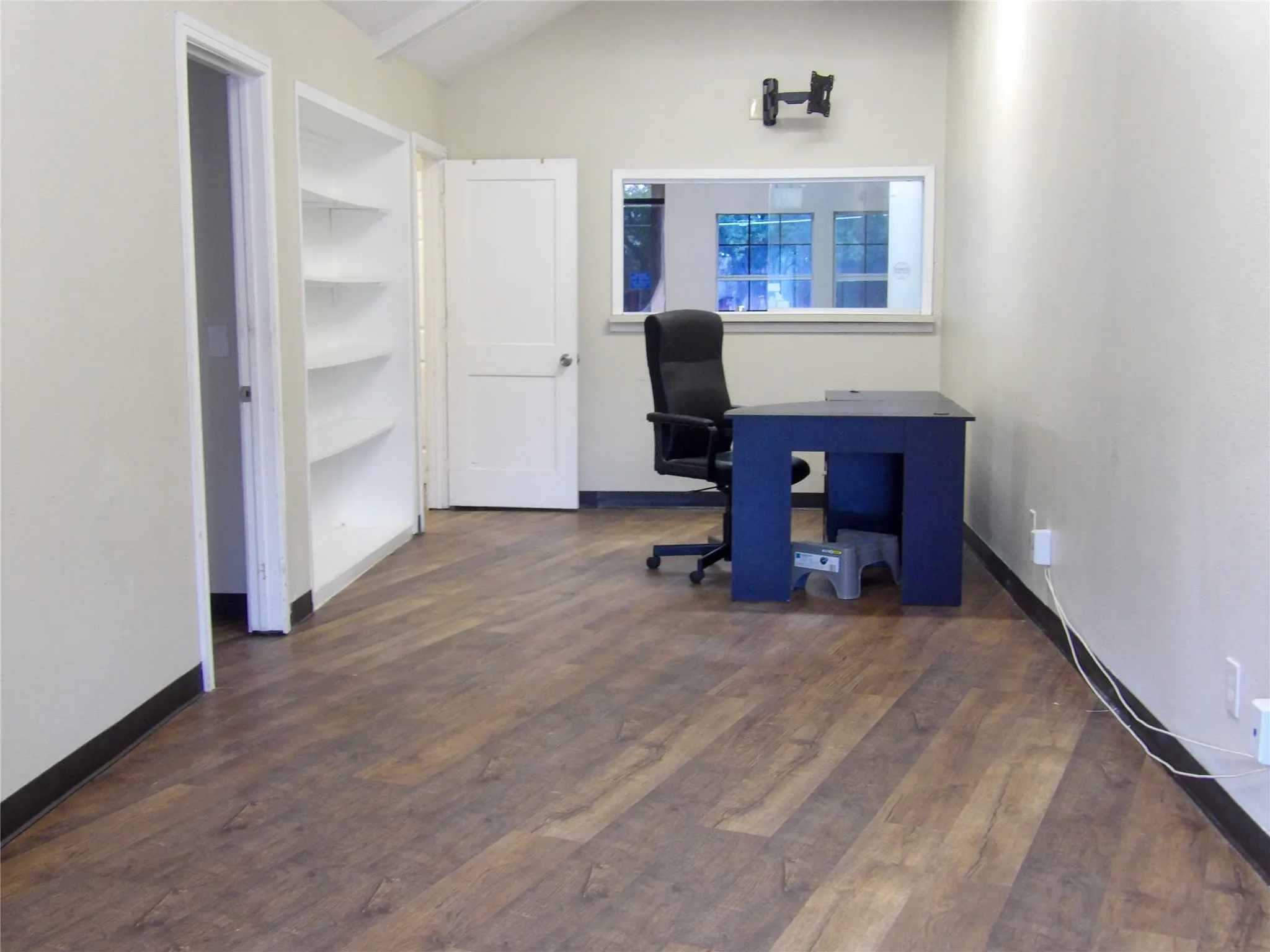 Huge receptionist Spacious room featuring wood-finish flooring, vaulted ceiling, built-in shelving, and a transom window