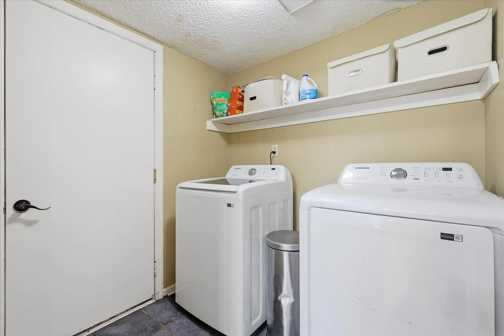 Dedicated laundry area featuring a white washer and dryer, a built-in wall shelf, and slate-finish flooring