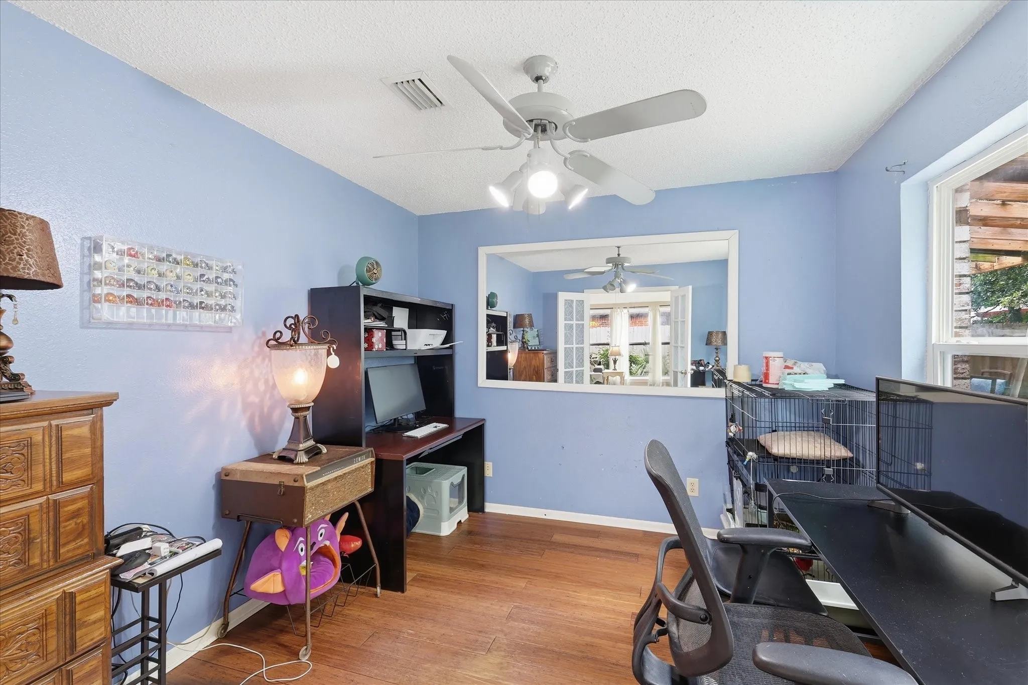 Versatile room featuring wood-finish flooring, a ceiling fan with integrated lighting, and multiple windows
