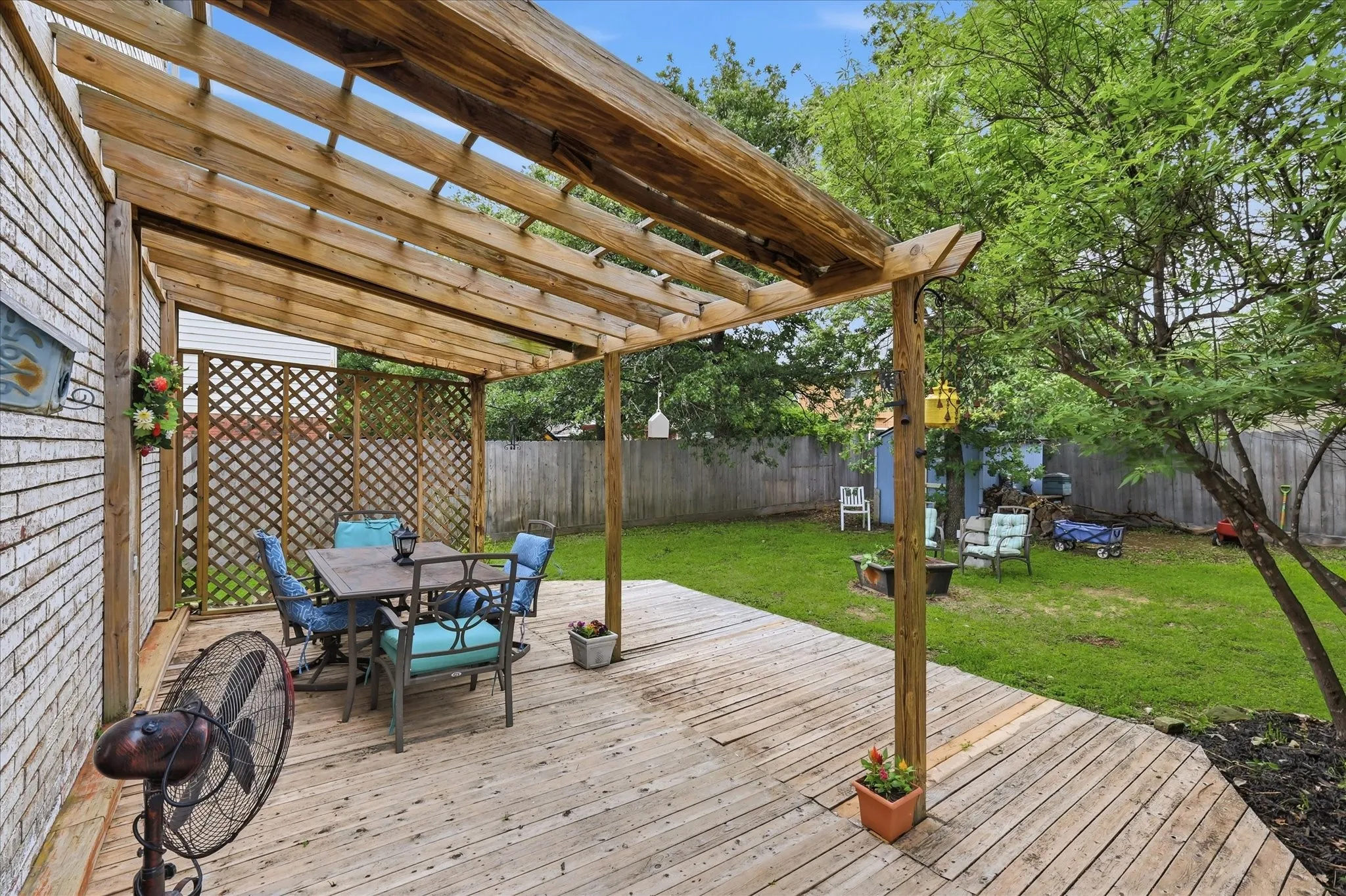 Expansive wood deck with a built-in pergola, lattice privacy screen, and direct access to the spacious backyard featuring mature trees