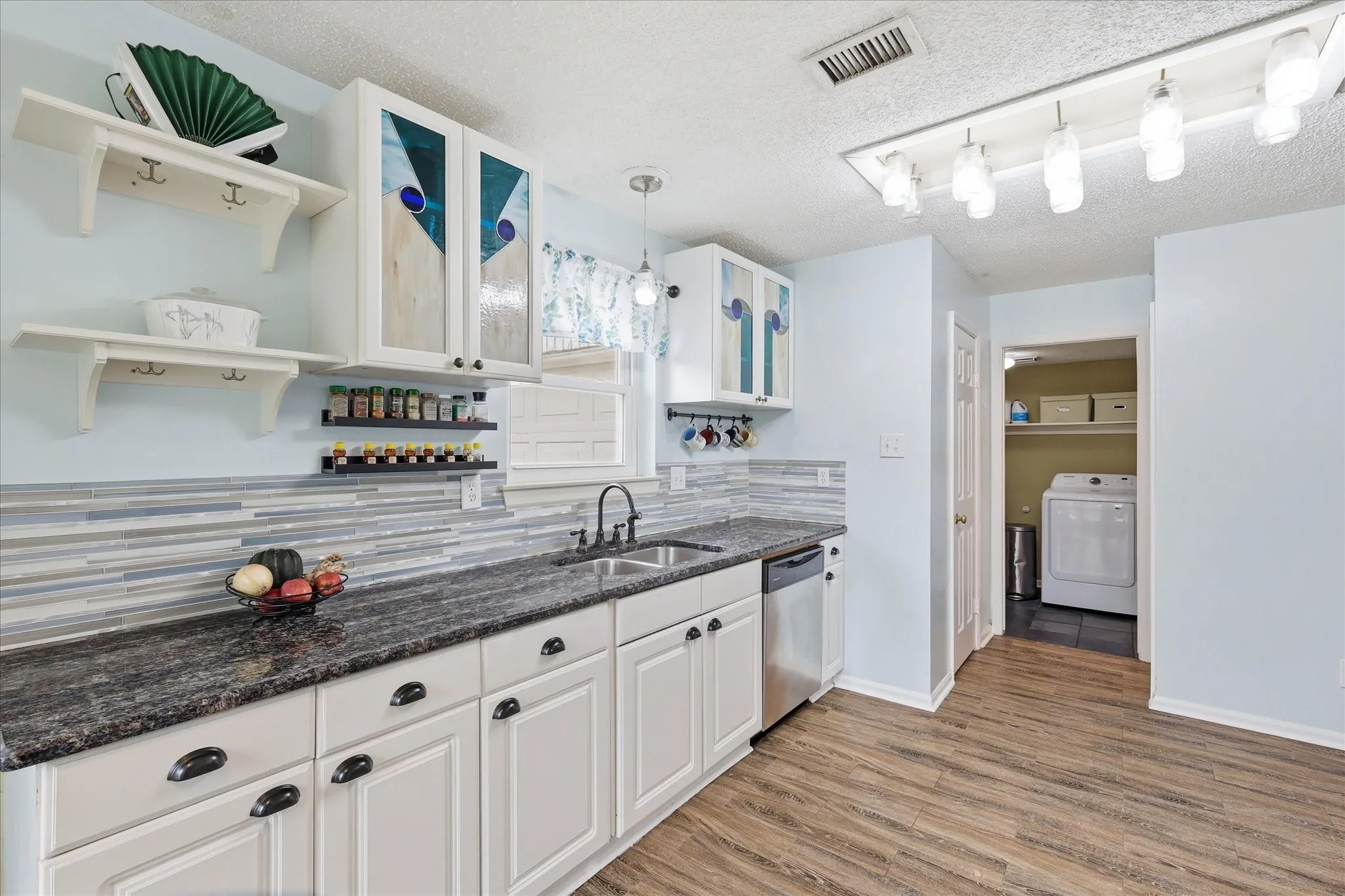 Bright kitchen featuring wood-finish flooring, white cabinetry, and a large pantry