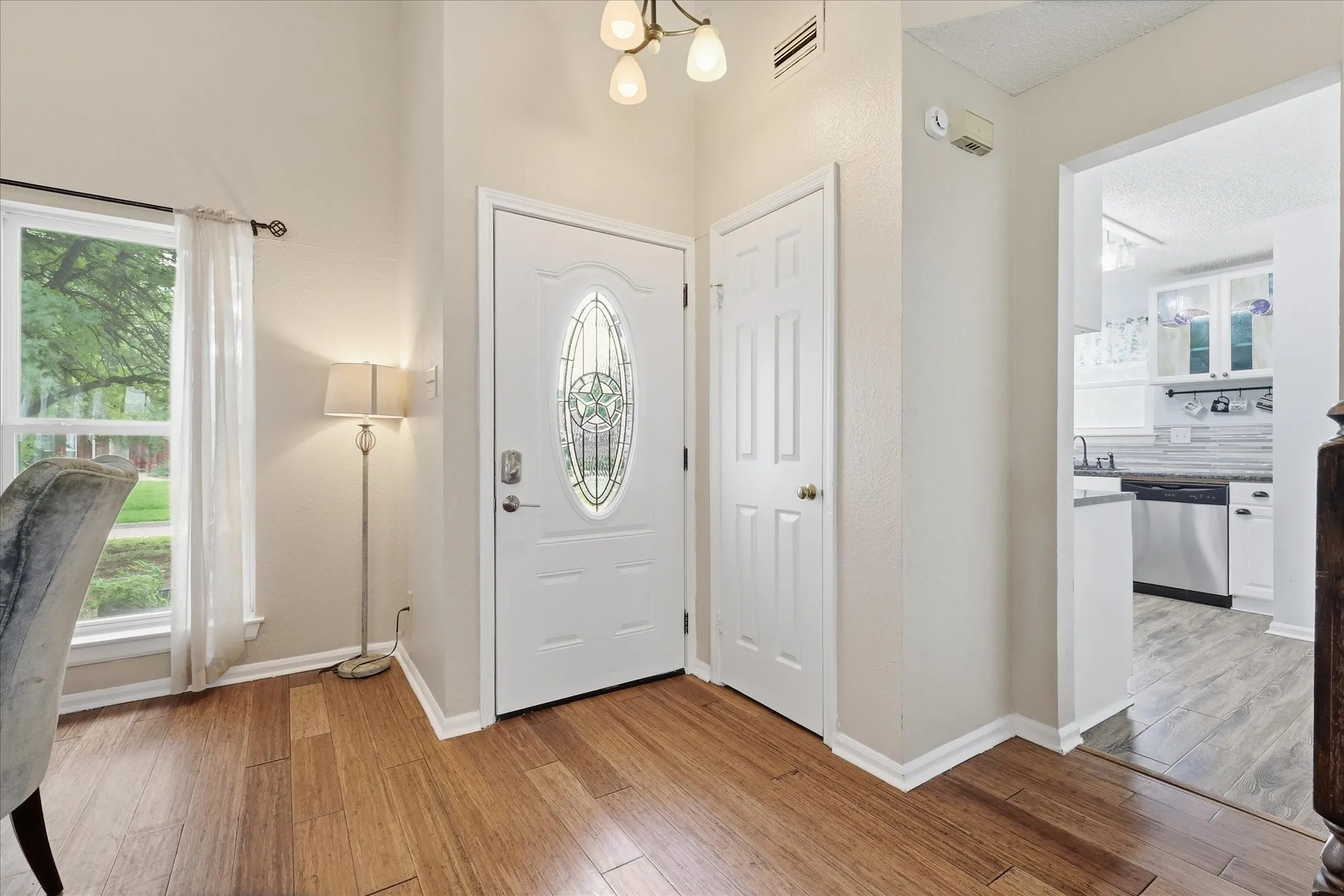 Entryway featuring wood-finish flooring, a white front door with decorative glass, and a vaulted ceiling