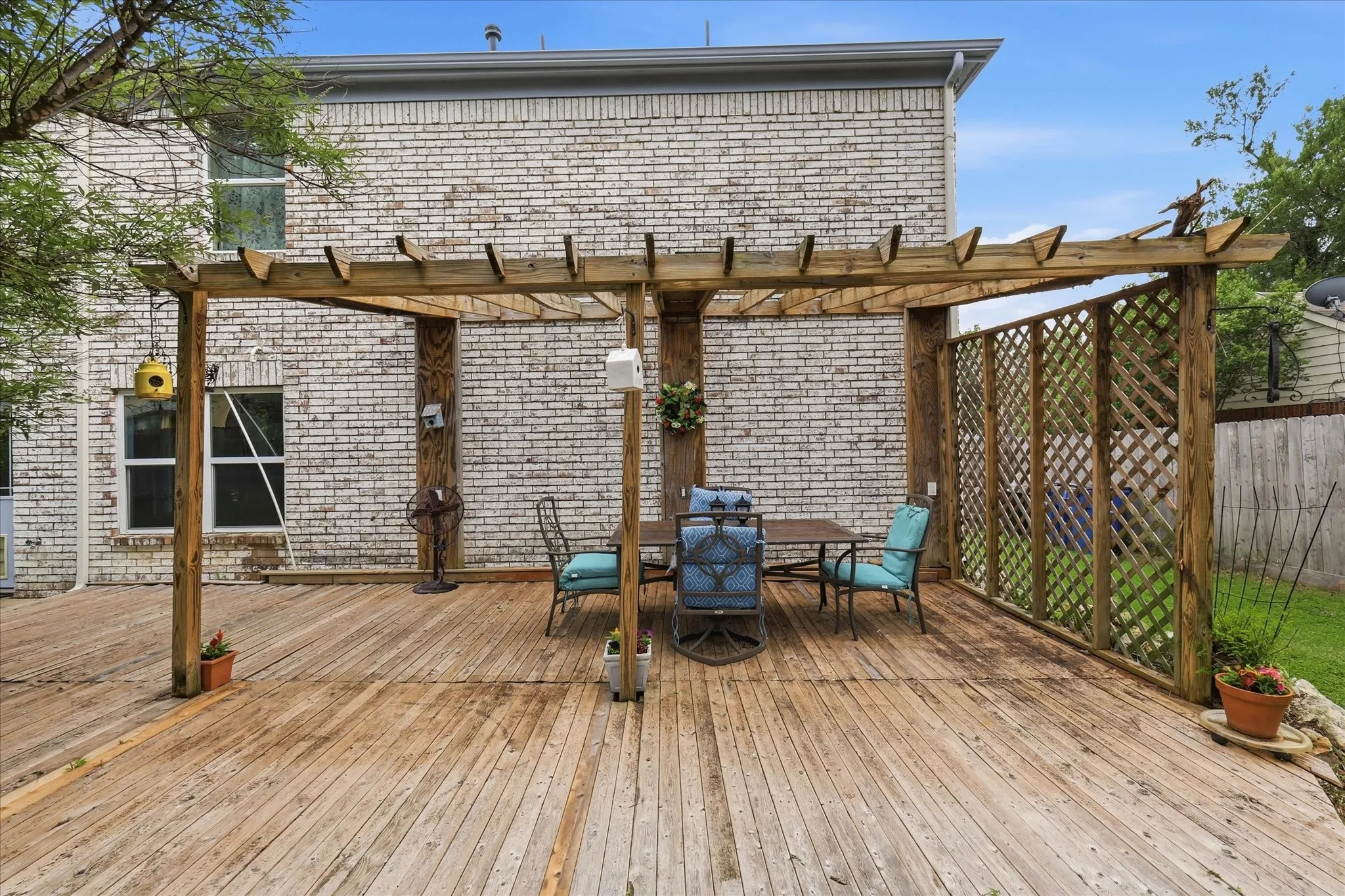 Spacious wood deck featuring a pergola structure and lattice privacy screening
