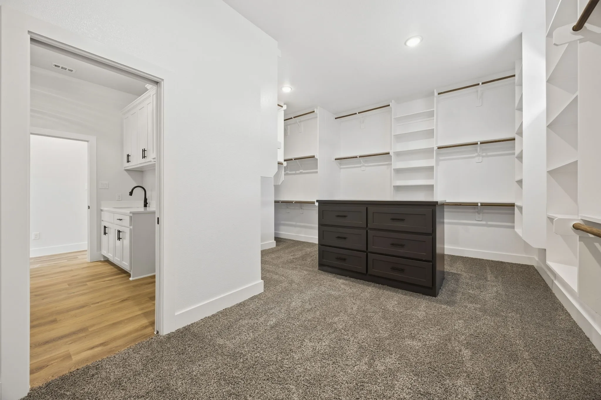 Spacious walk-in closet with extensive built-in shelving, hanging rods, and a central dresser