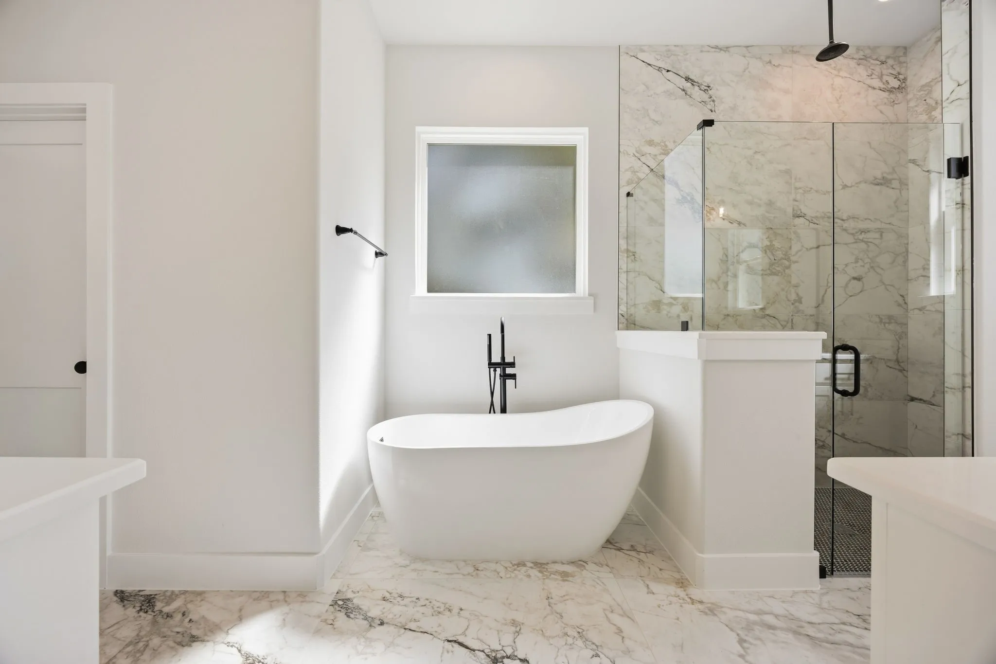 Freestanding soaking tub with matte black fixtures, marble-patterned tile flooring, frameless glass shower enclosure, and a built-in privacy window