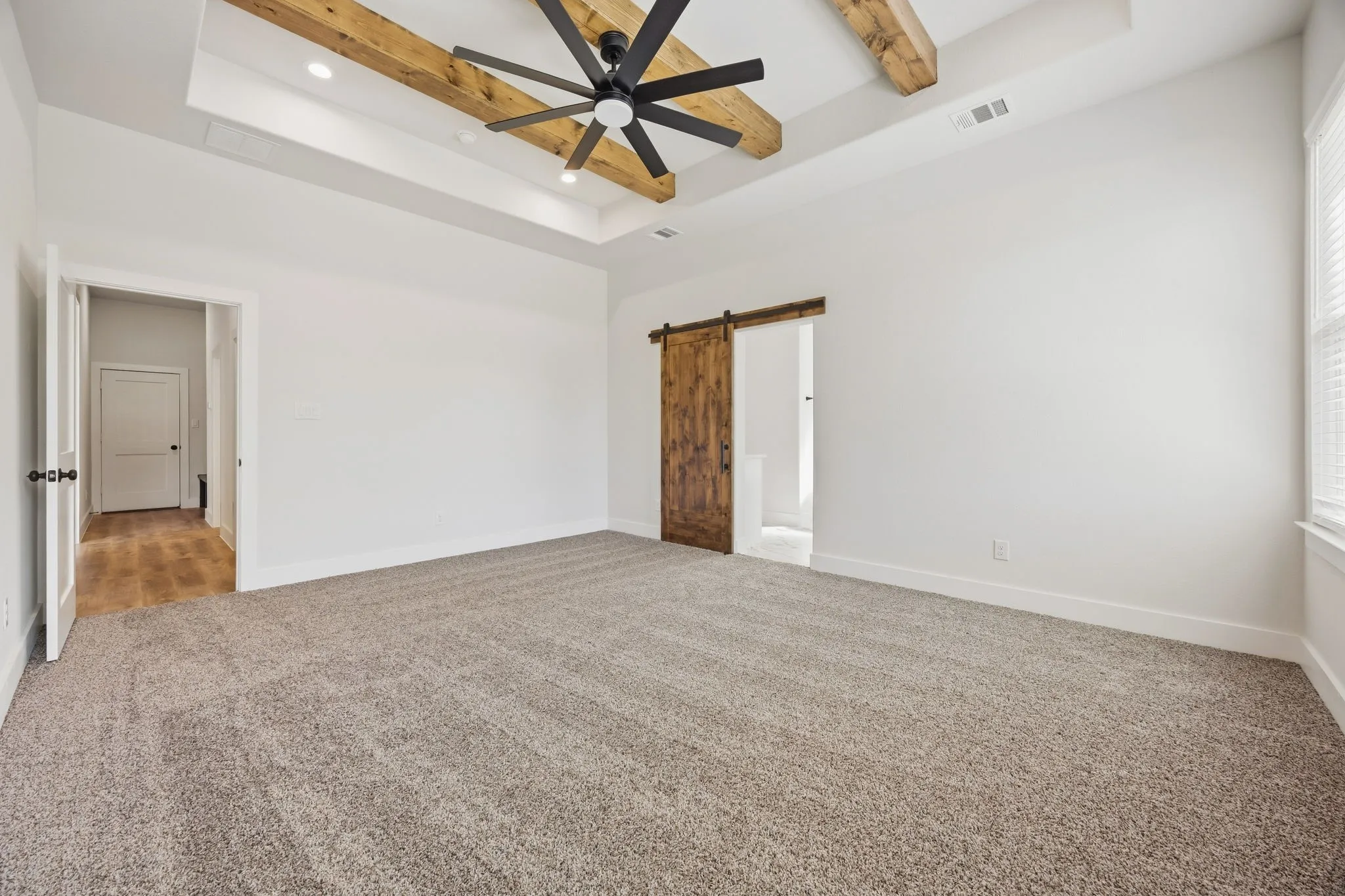 Tray ceiling with exposed wood beams, recessed lighting, and a ceiling fan