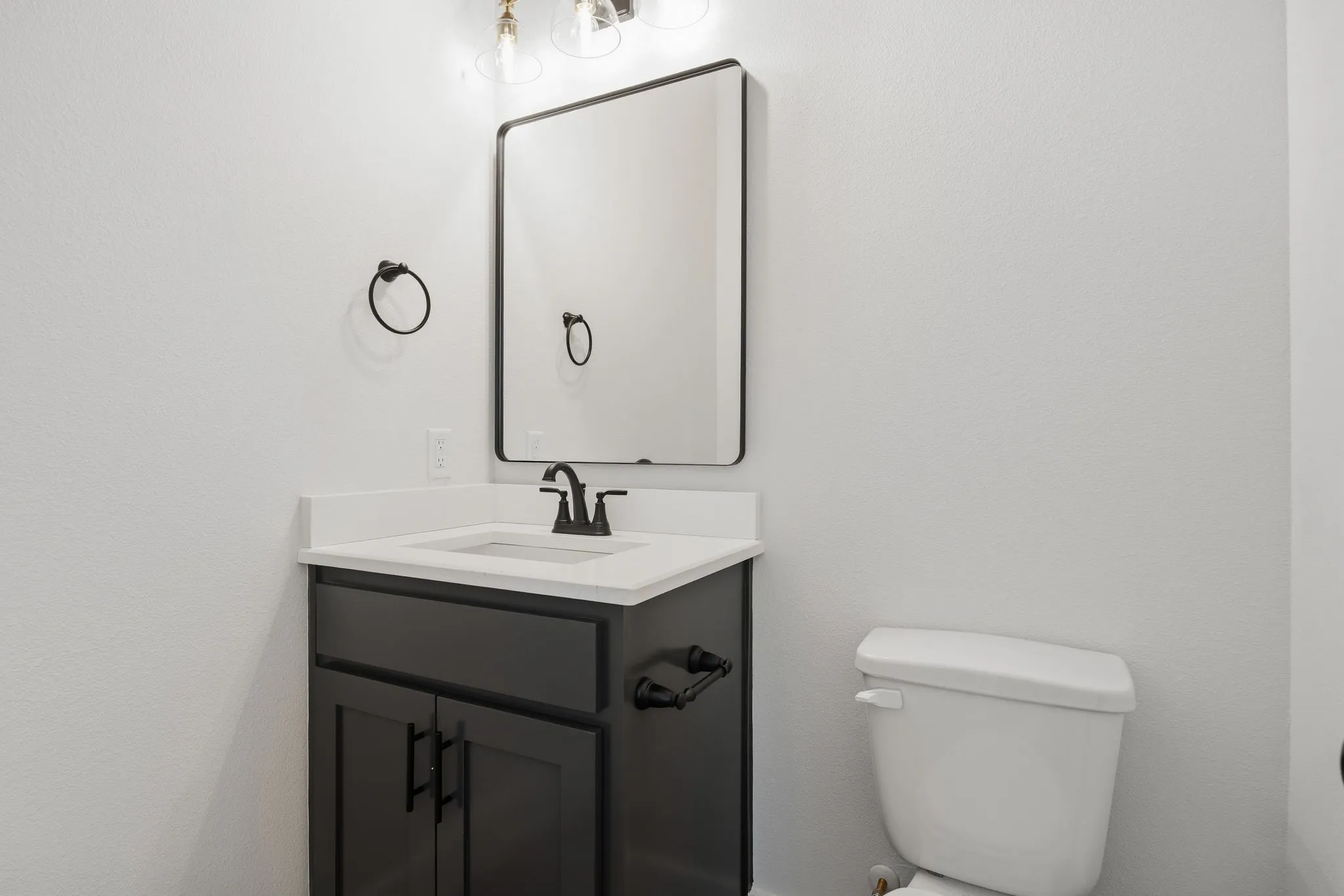 Vanity with white countertop, dark cabinetry, and matte black hardware