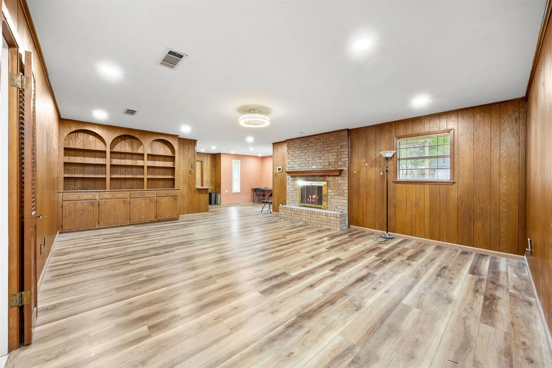 Spacious living area featuring wood-finish flooring, recessed lighting, and wood paneling throughout
