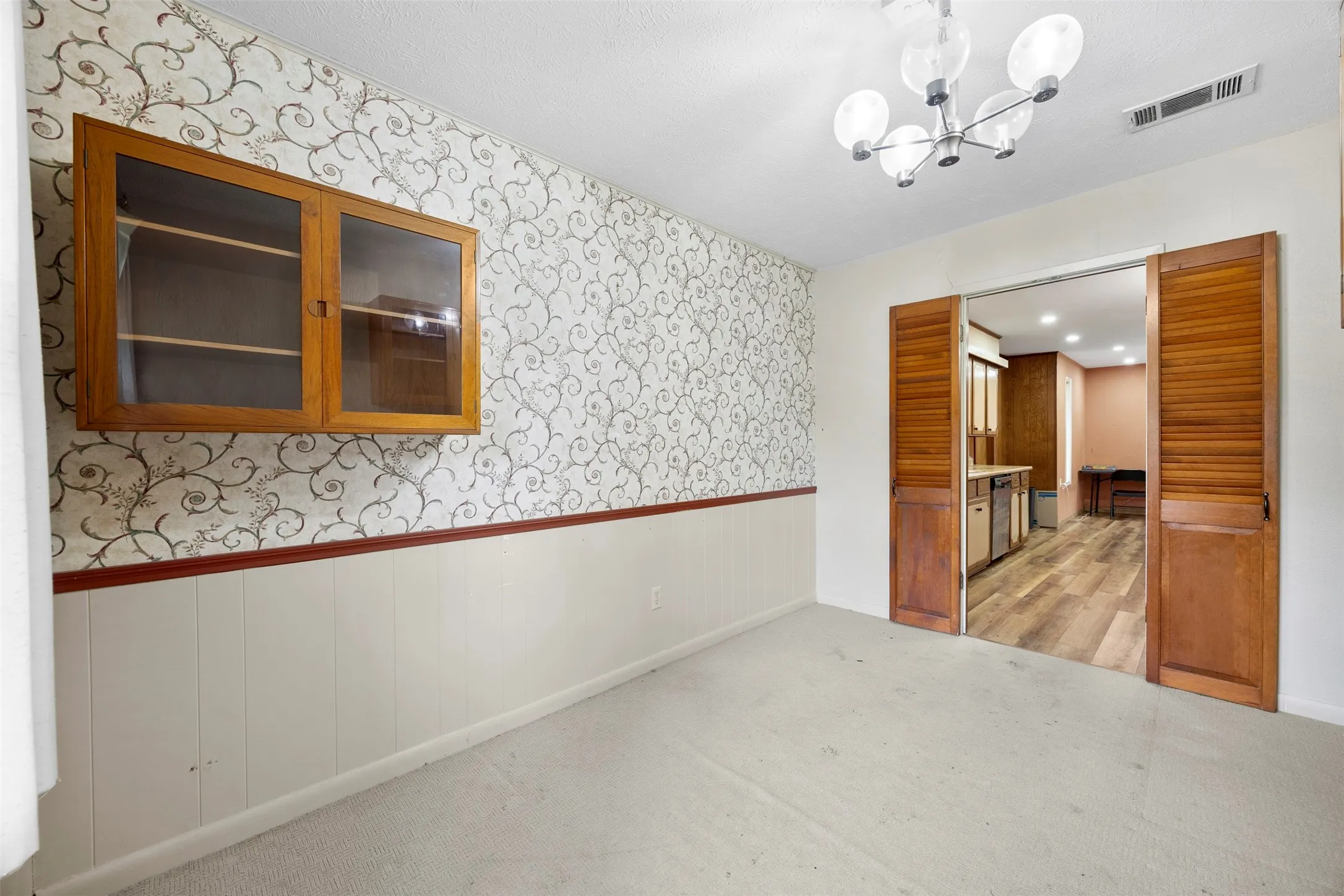 Interior space featuring a patterned wallpaper accent wall with chair rail and wainscoting