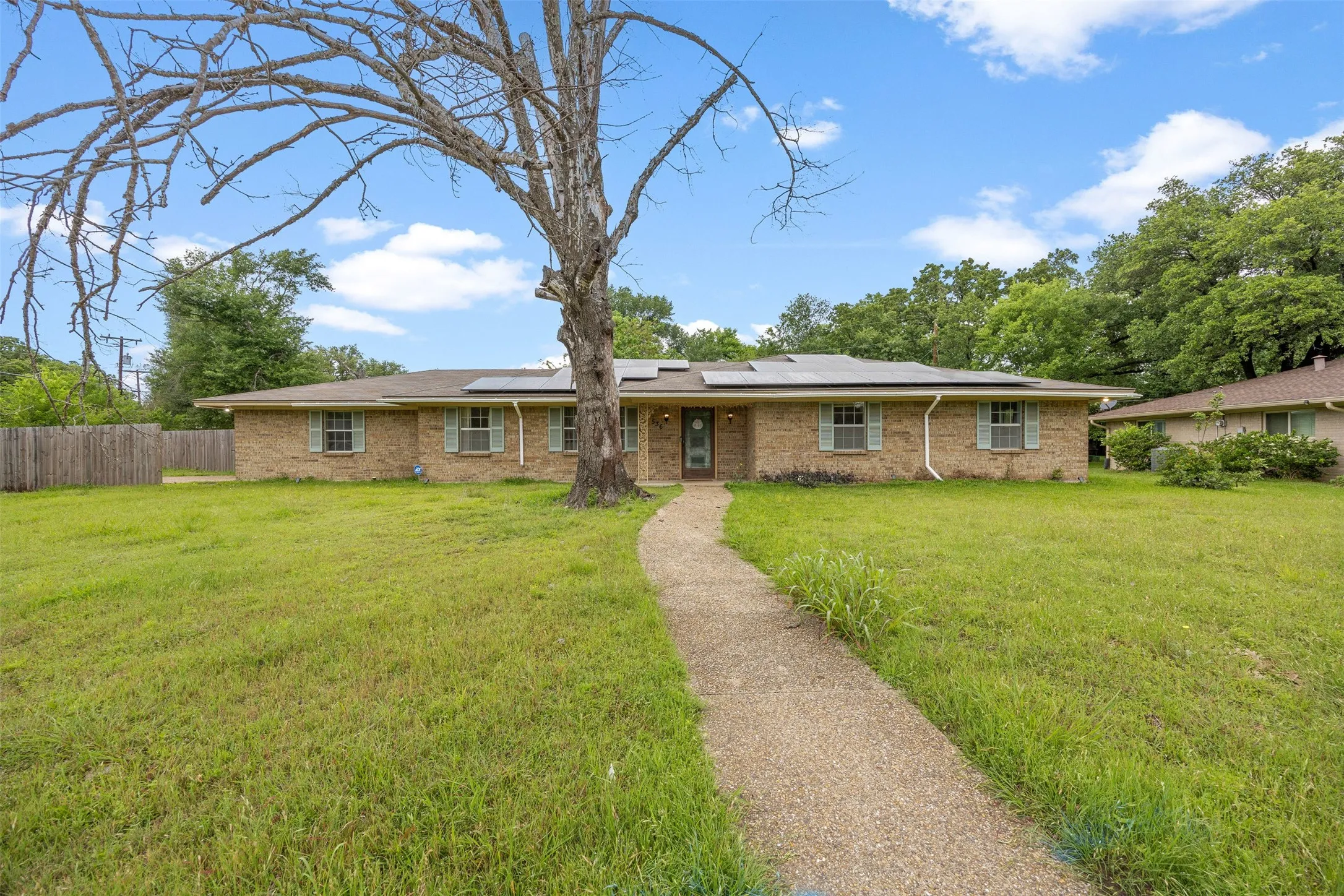 Brick ranch-style residence featuring a prominent front lawn and a concrete walkway