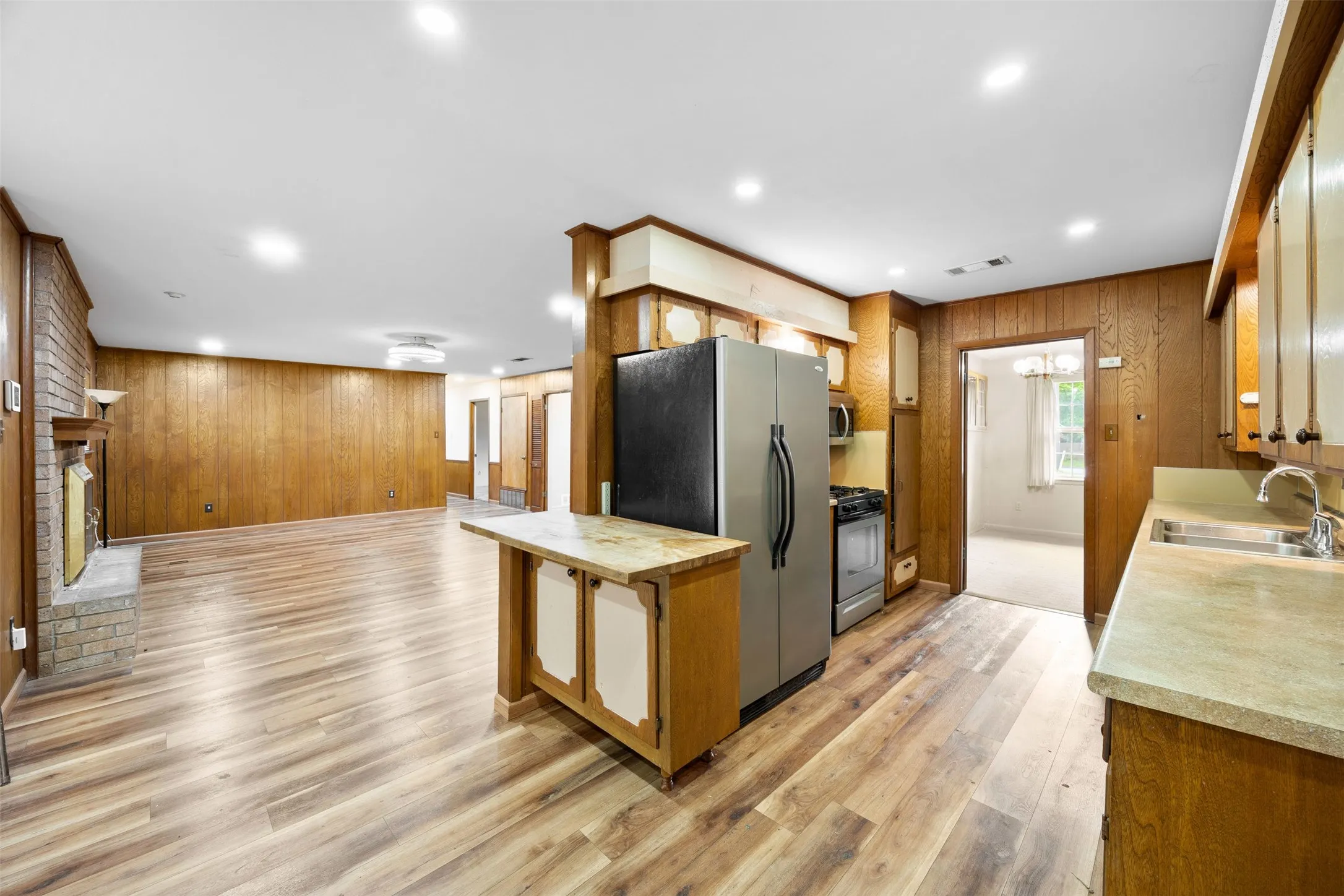Open concept kitchen and living area featuring wood-finish flooring, wood paneling, and recessed lighting