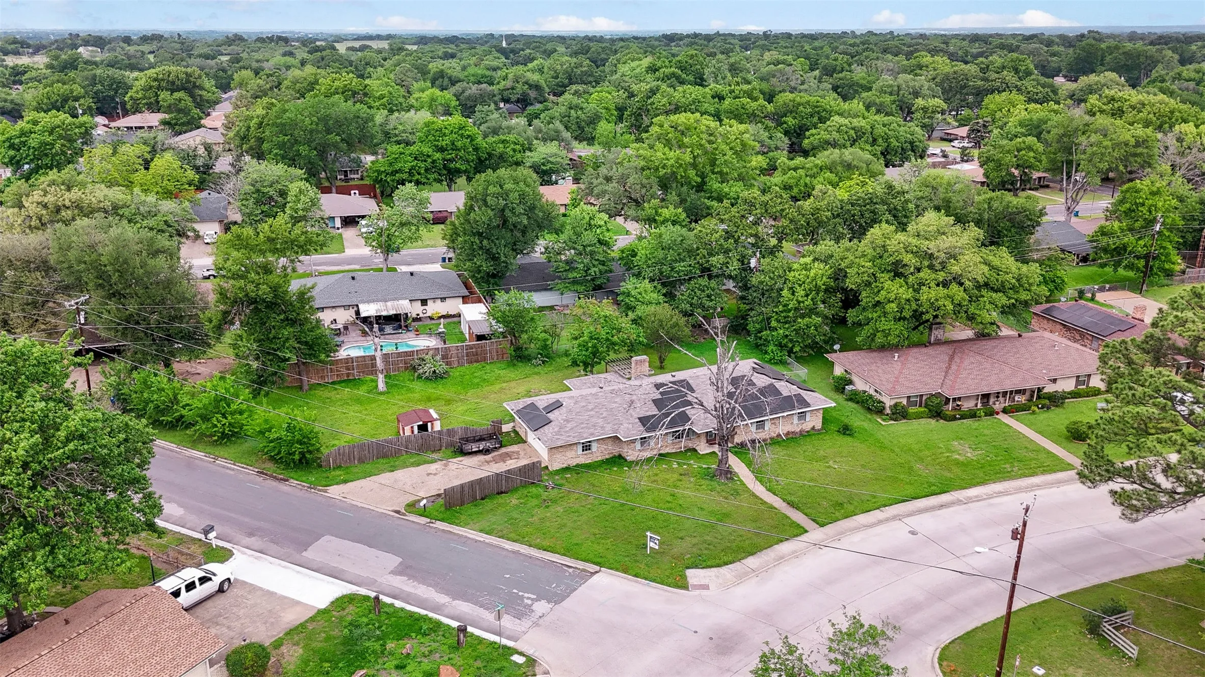 Corner lot property featuring mature landscaping and a well-maintained lawn