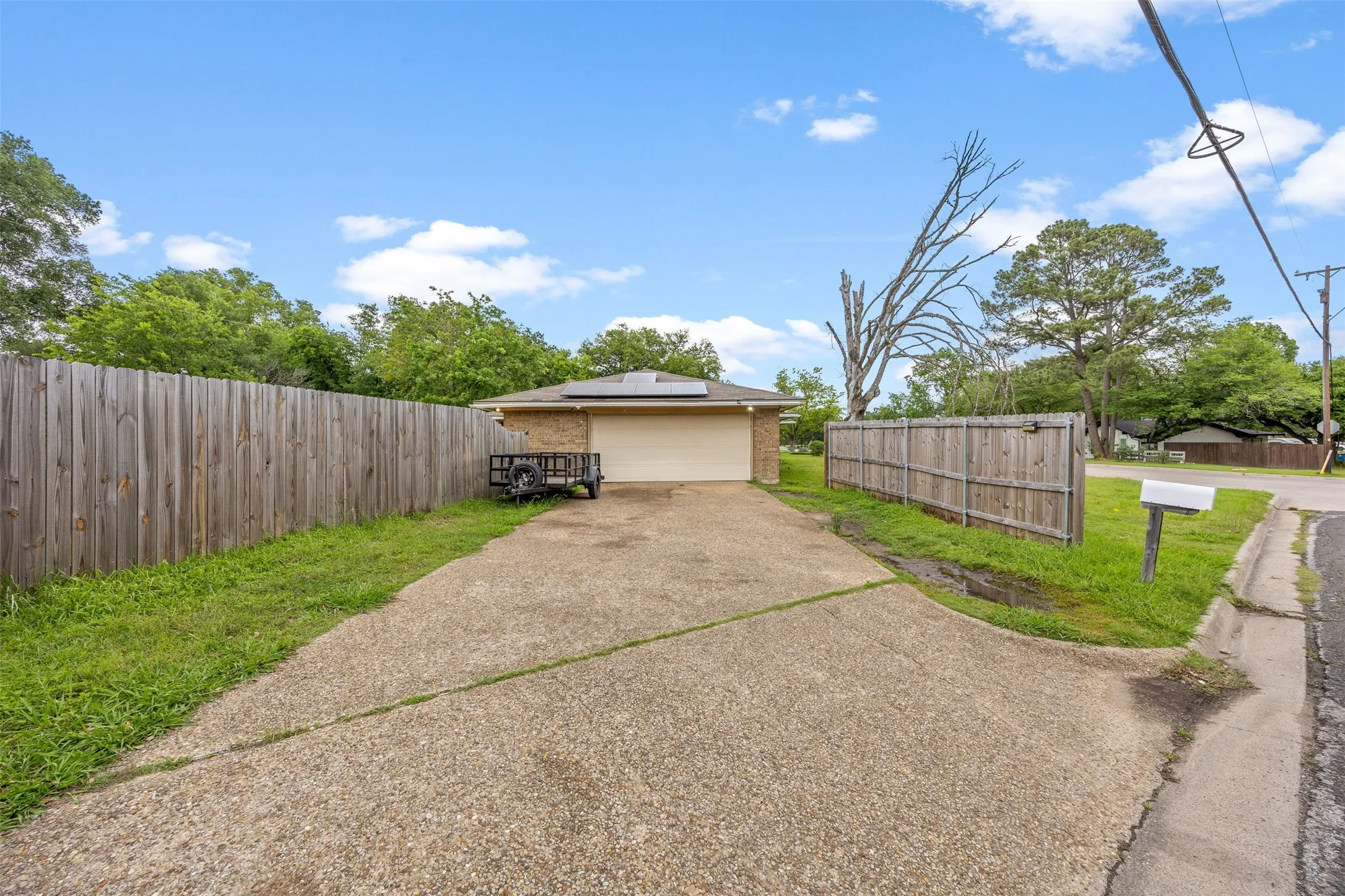 Single-story brick exterior featuring an attached two-car garage, concrete driveway, and side yard with wood privacy fencing