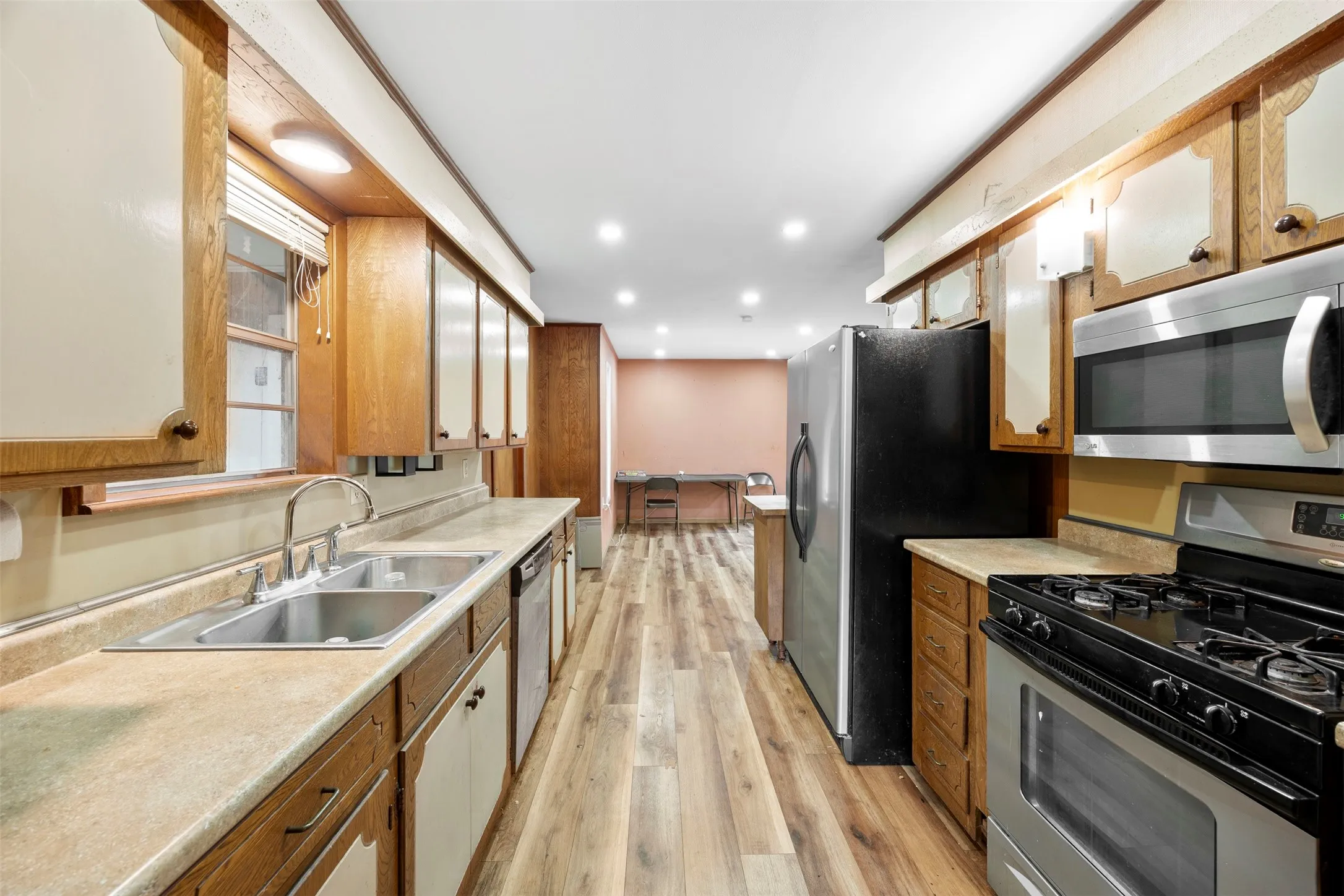 Galley-style kitchen featuring wood-finish flooring, recessed lighting, and a stainless steel appliance suite