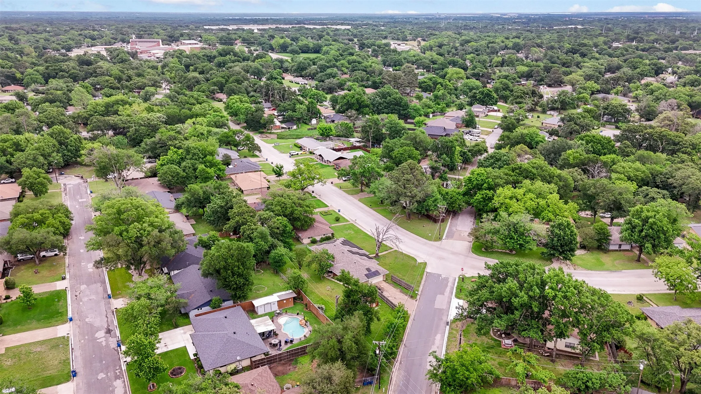 Aerial perspective showcasing a residential neighborhood with abundant mature trees