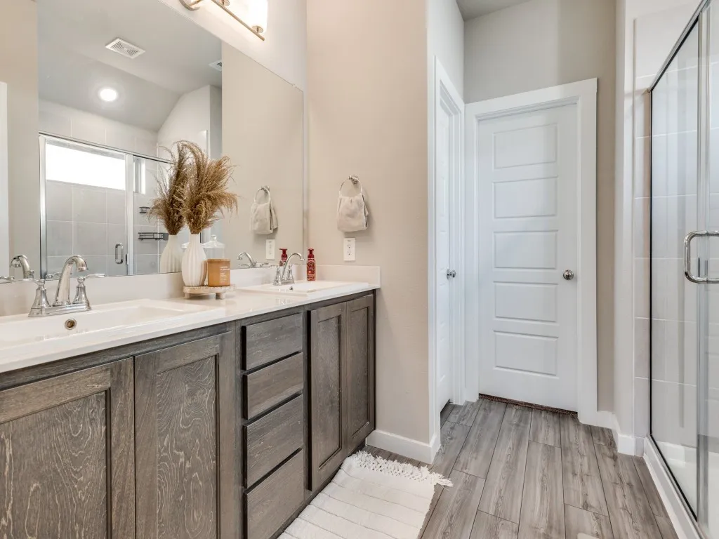 Bathroom featuring a dual vanity with undermount sinks, wood-finish cabinetry, and light-toned countertops
