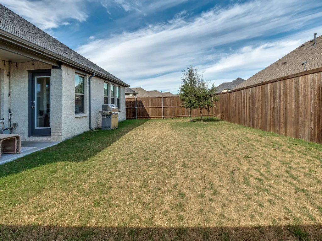 Spacious backyard featuring a privacy fence, a young tree, and a concrete patio directly accessible from the dwelling