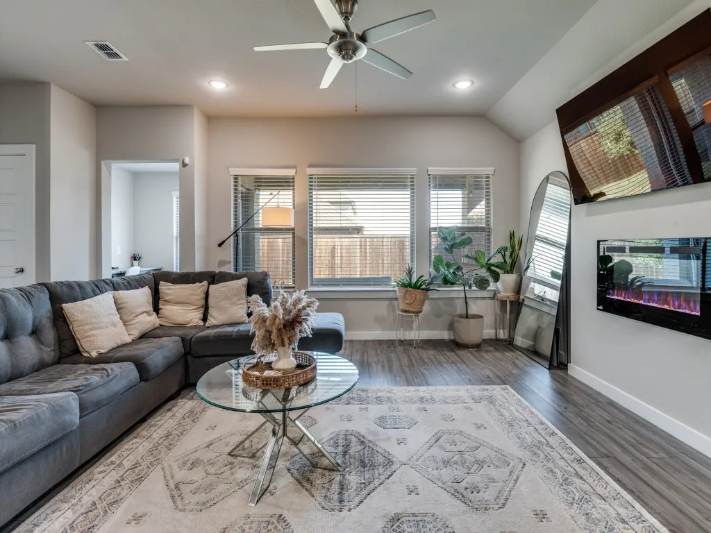 Living area featuring wood-finish flooring, recessed lighting, a ceiling fan, multiple windows with blinds, and a built-in electric fireplace