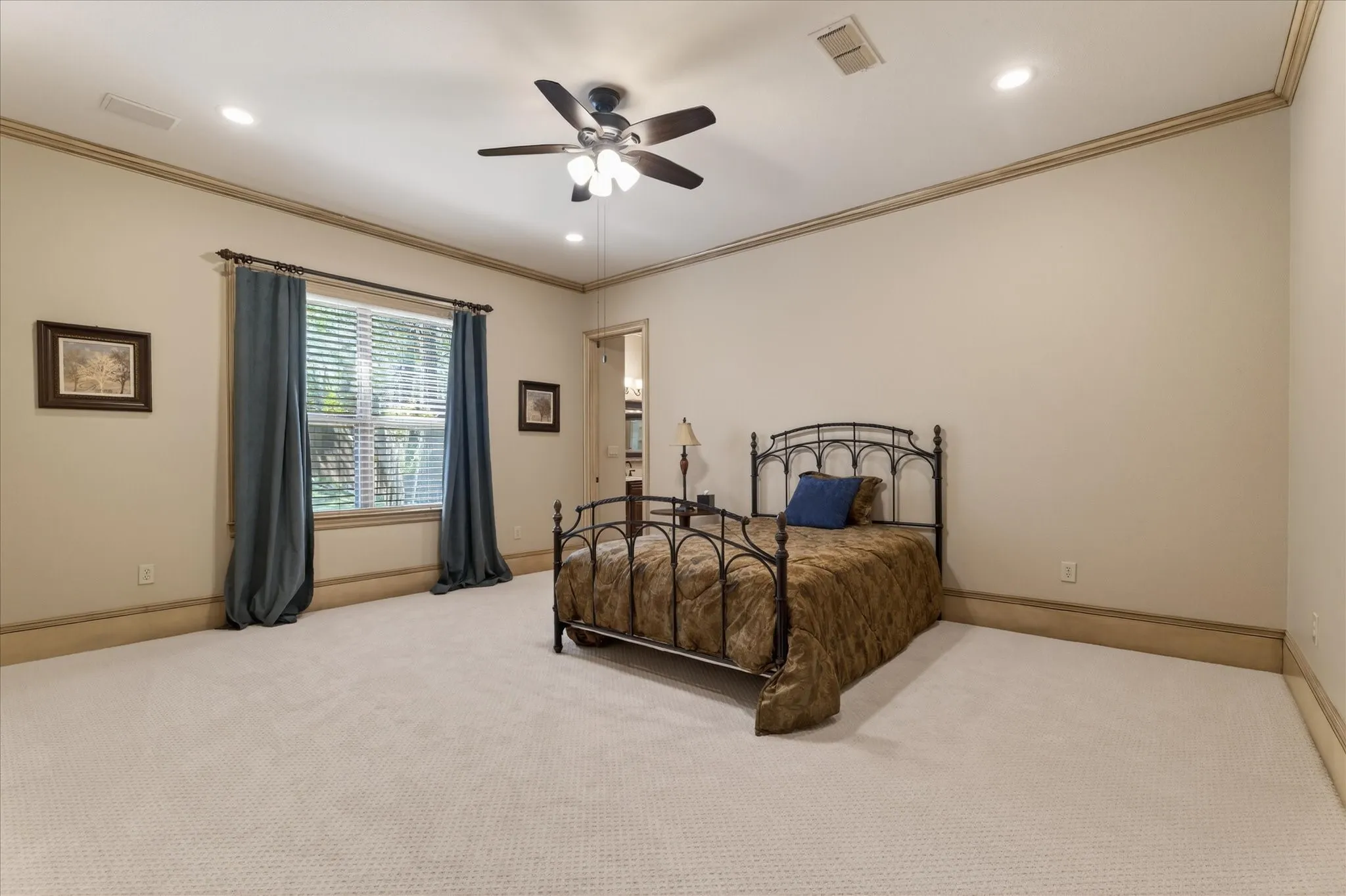 Carpeted room featuring a ceiling fan with integrated lighting, recessed lighting, crown molding, and a large window with blinds