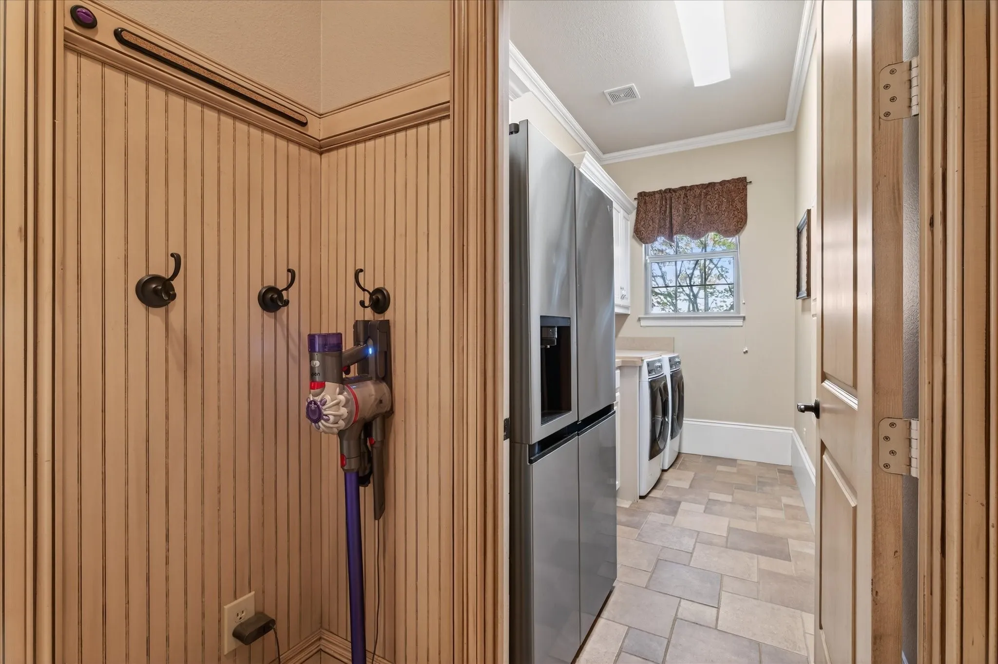 Utility room with tile flooring, built-in cabinetry, and a window