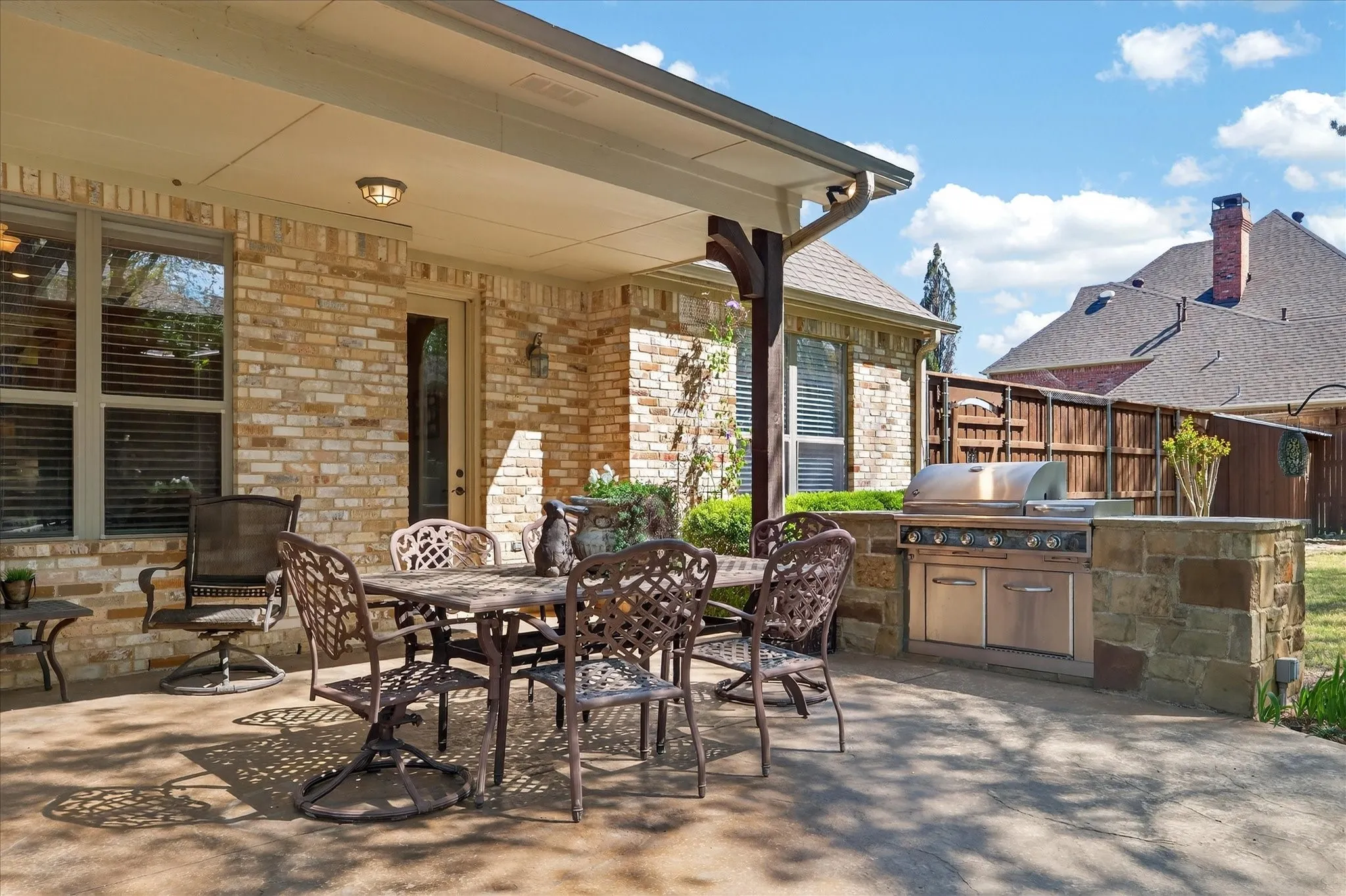 Covered patio with a built-in outdoor grill, stone surround, and concrete flooring