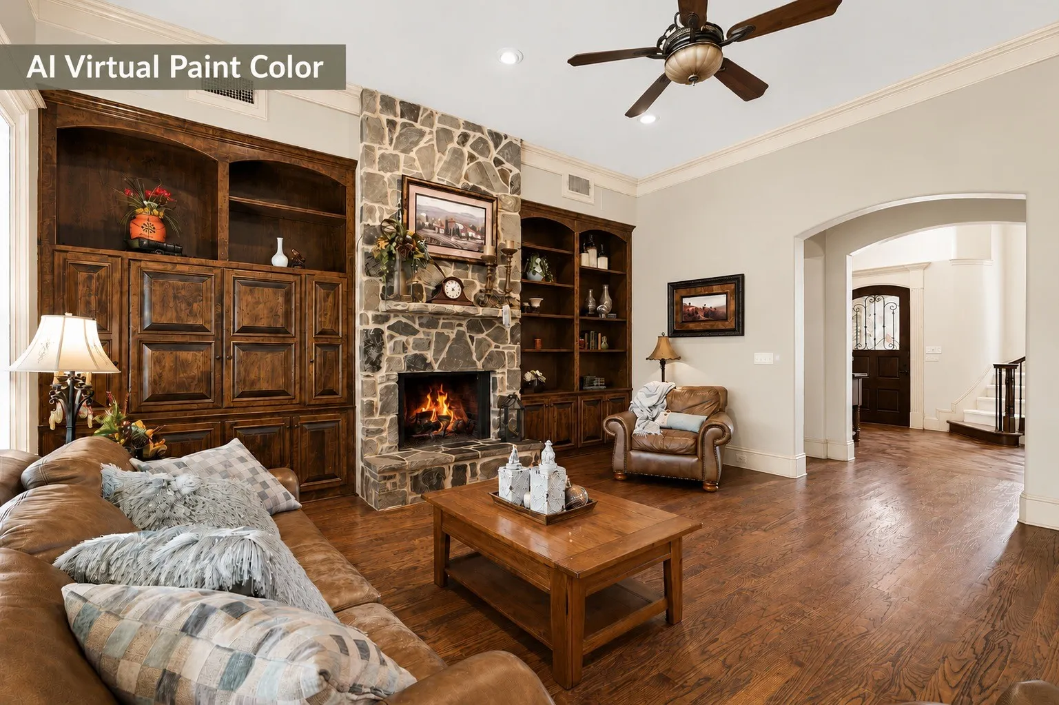 Living area featuring a stone-clad fireplace, integrated wood-finish shelving and cabinetry, wood-finish flooring, and a ceiling fan