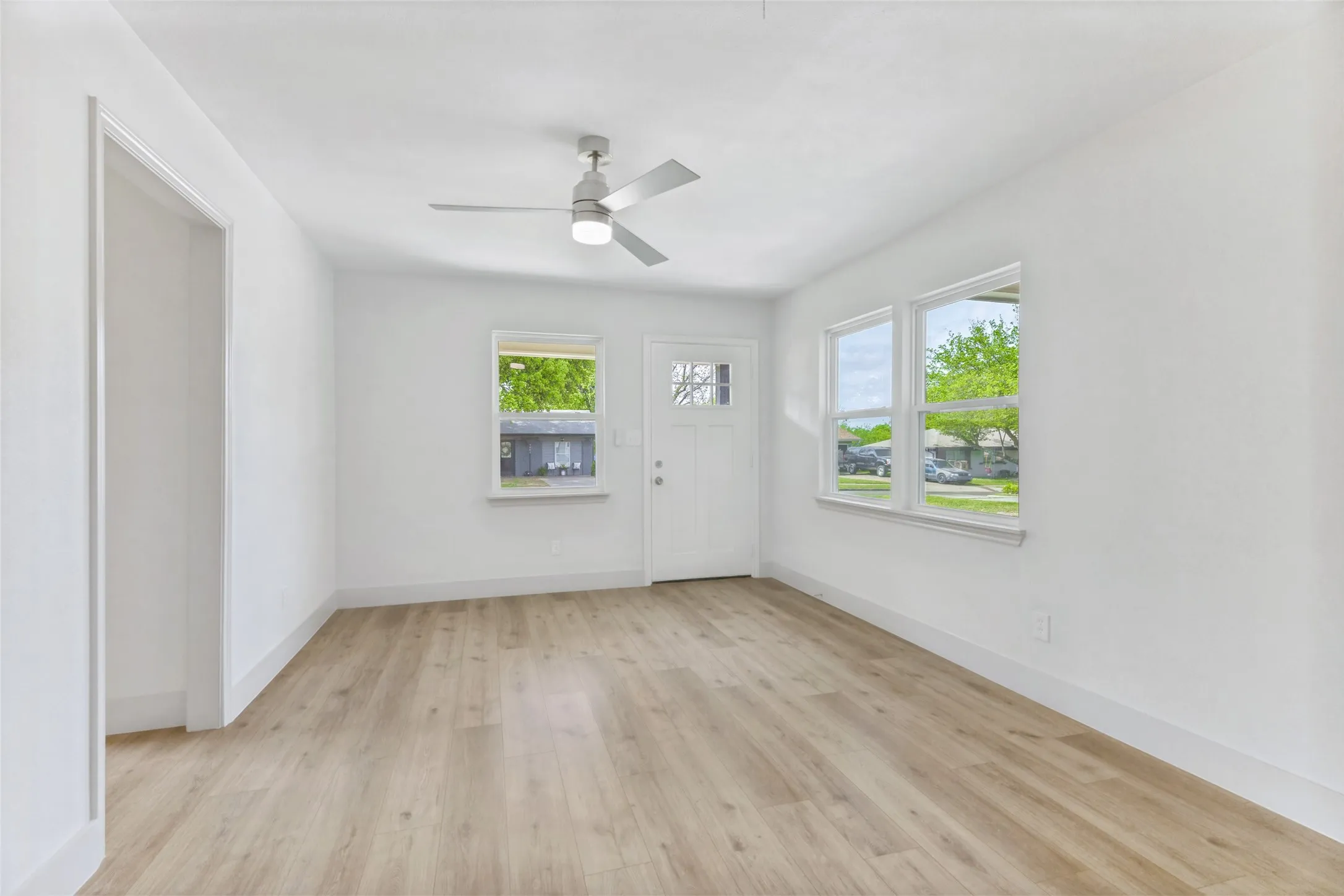 Bright room featuring light wood-finish flooring and crisp white walls