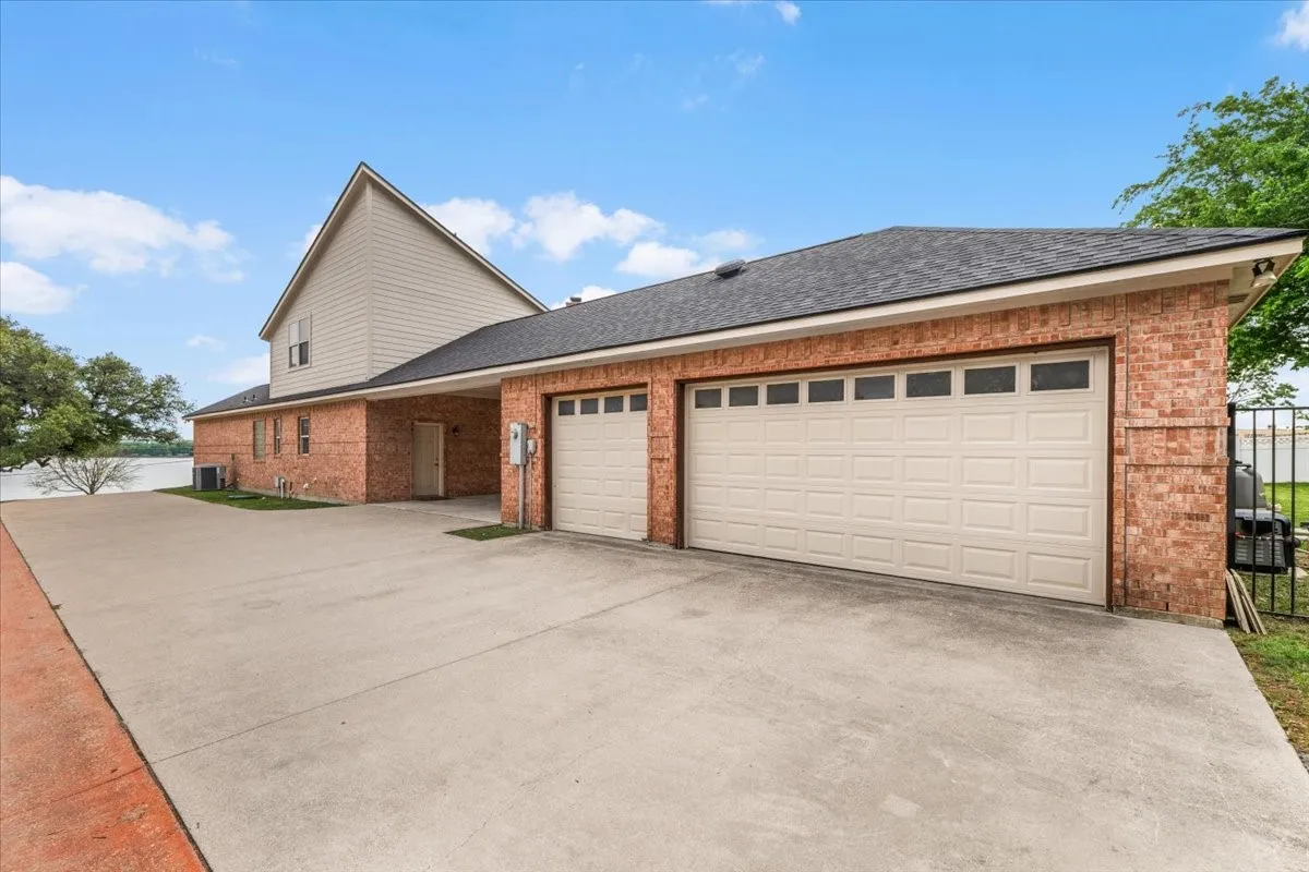 Brick and siding exterior featuring a multi-car garage with panel doors, a paved driveway, and covered entry
