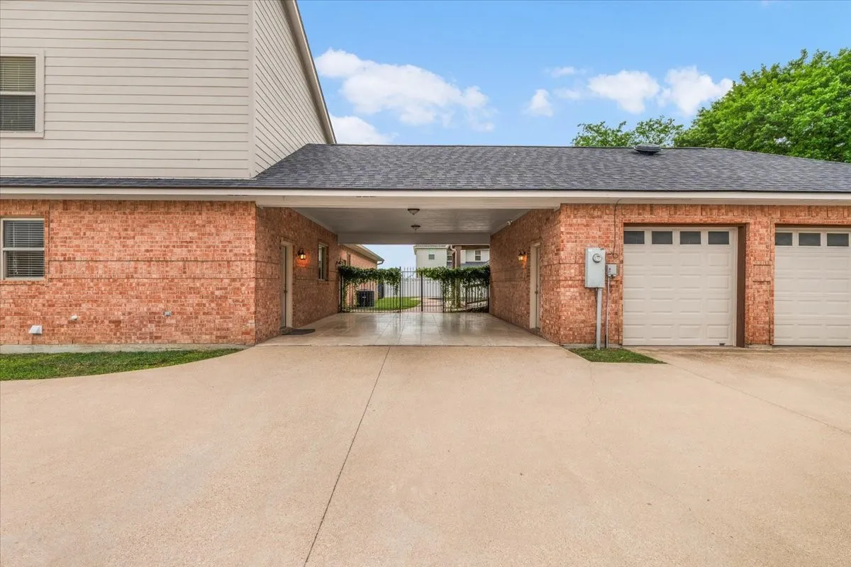 Brick exterior with an expansive concrete driveway and a covered porte-cochère