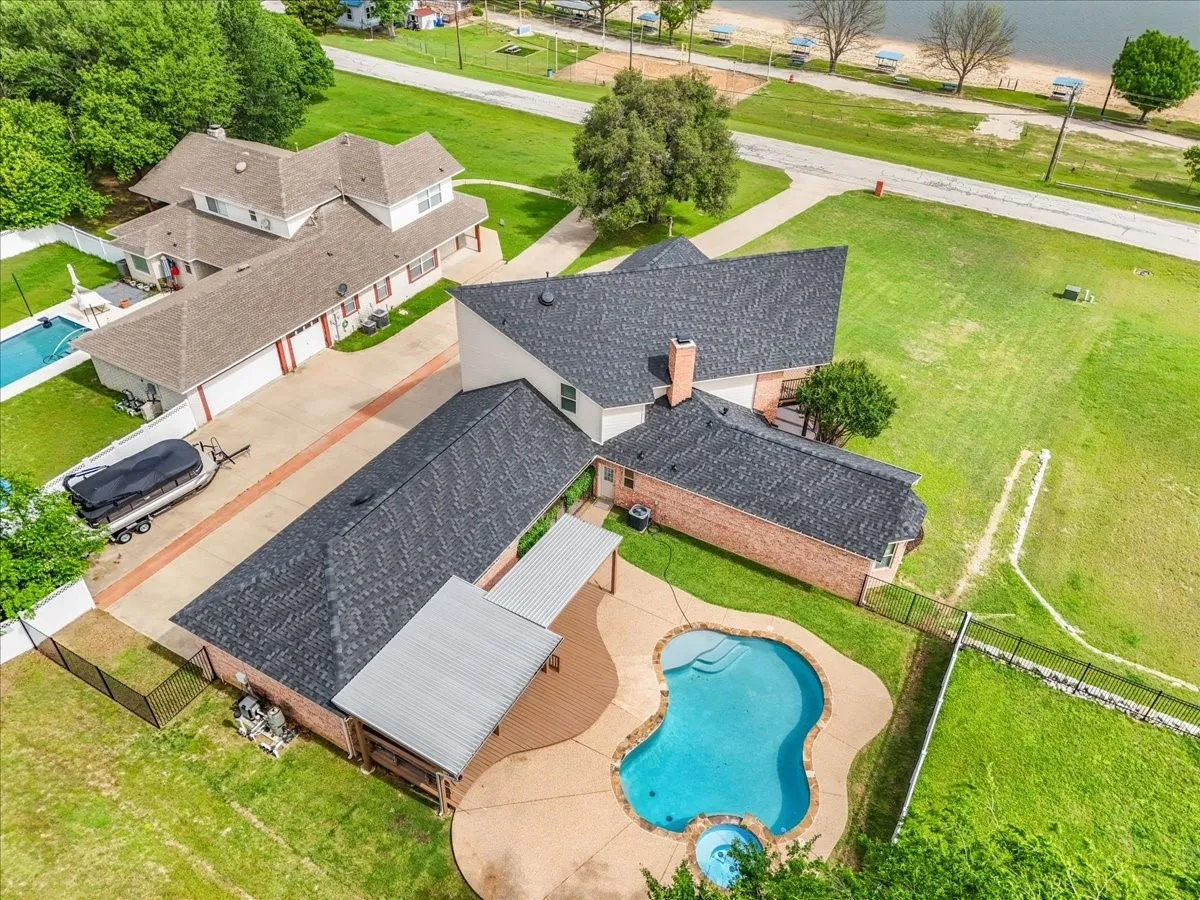 Residential property featuring a freeform swimming pool with integrated spa, a concrete pool deck, and an extensive wood deck with an attached covered patio