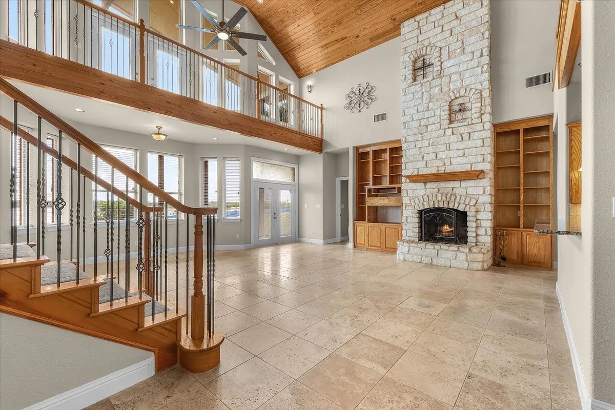 Great room featuring a stone fireplace with a wood mantle, integrated built-in shelving, and tile flooring