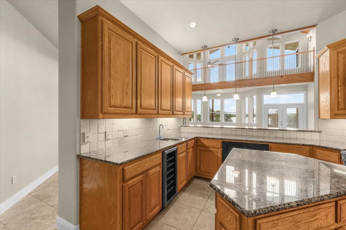Kitchen space with light wood cabinetry, granite countertops, and a tile backsplash