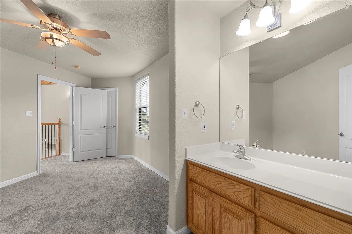 Bathroom vanity featuring a single basin sink, laminate countertop, and wood-finish cabinetry