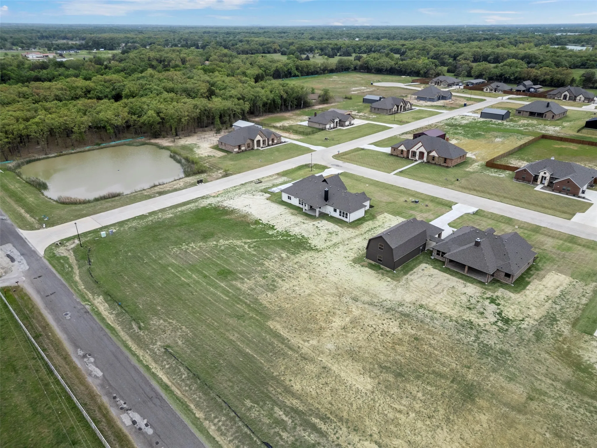 Newly constructed residential development featuring a private pond and surrounding wooded areas