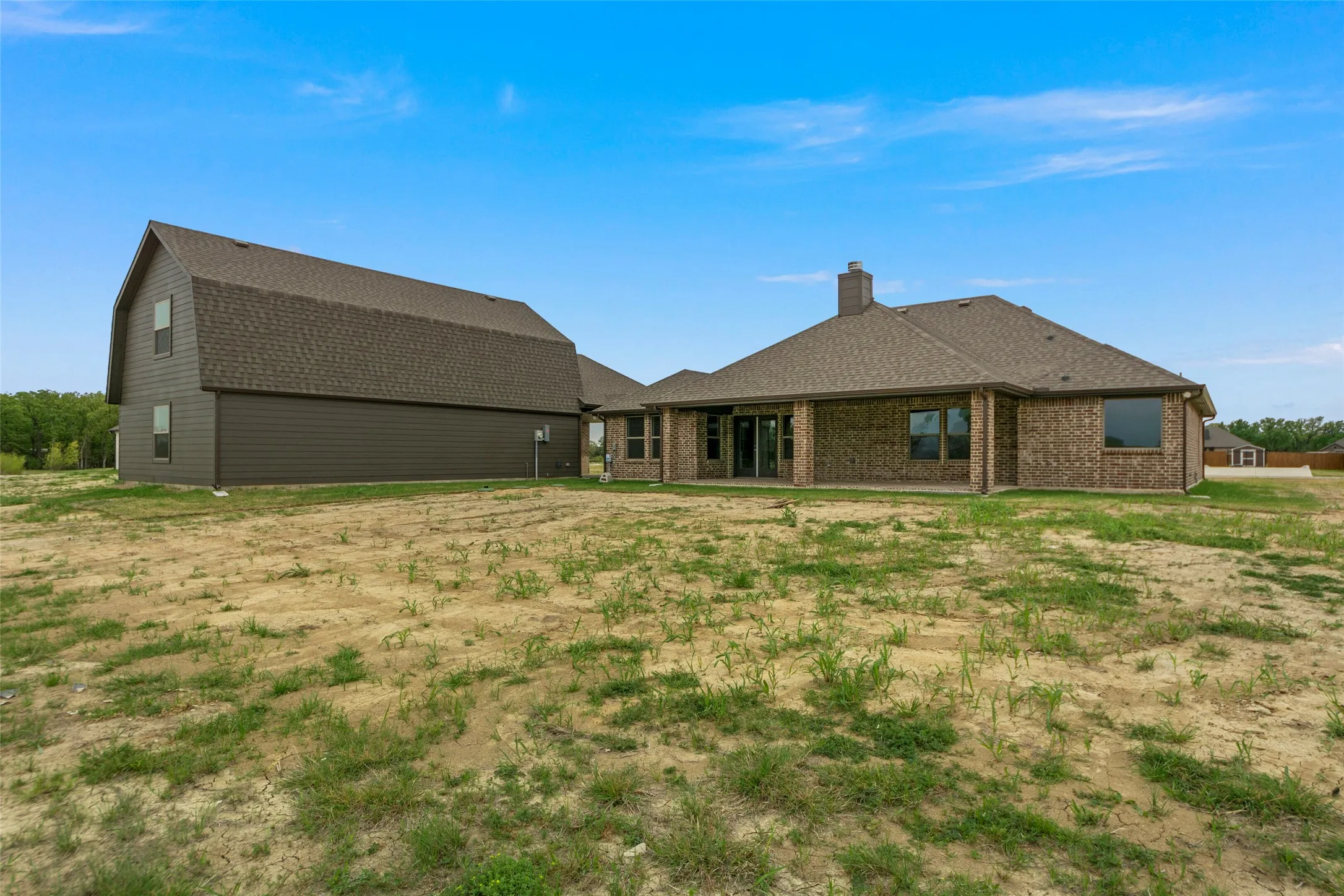 New construction home featuring brick exterior, covered patio, and a separate two-story structure with siding