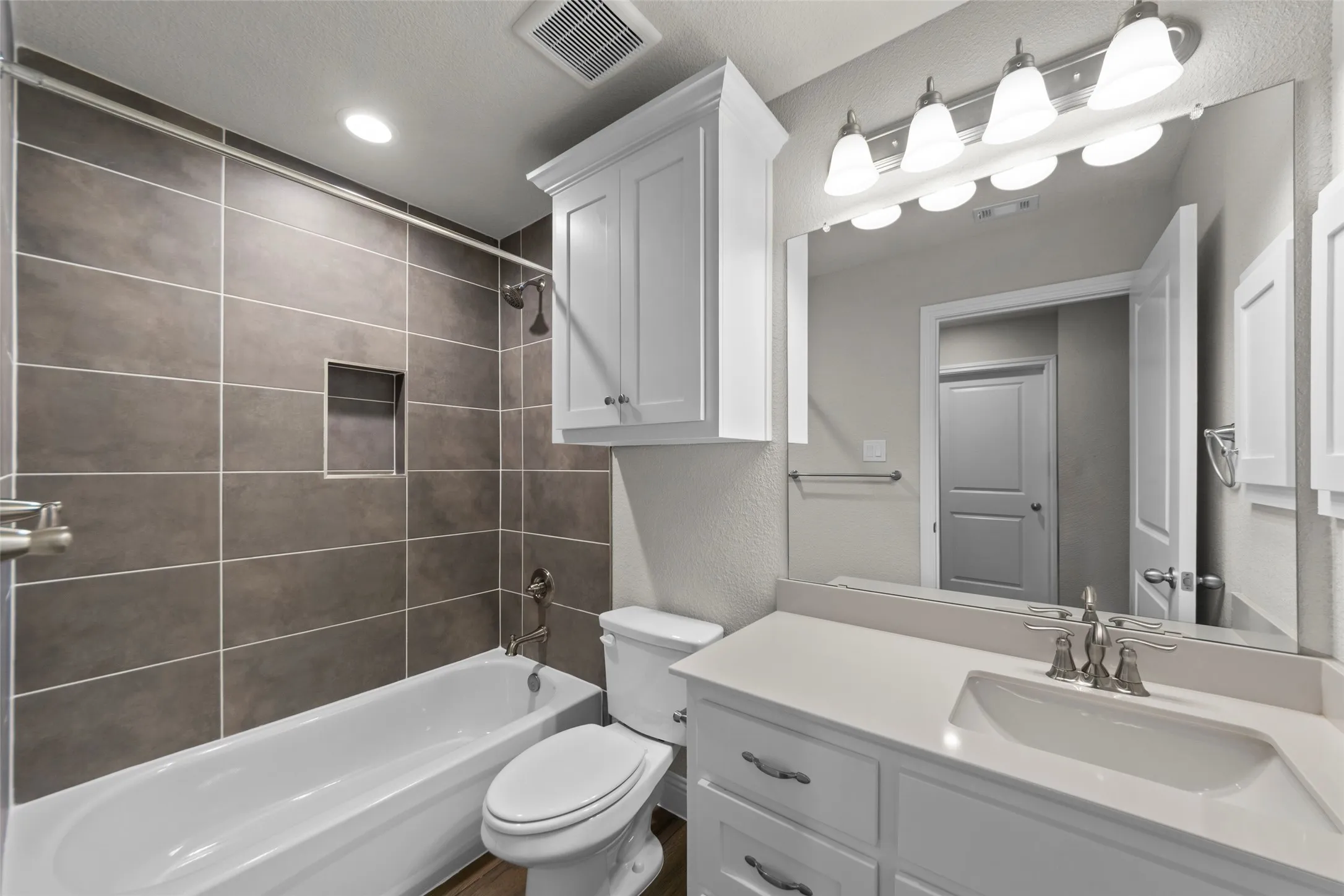 Bathroom featuring a white vanity with an integrated sink and brushed nickel faucet, a large mirror, and a five-light fixture