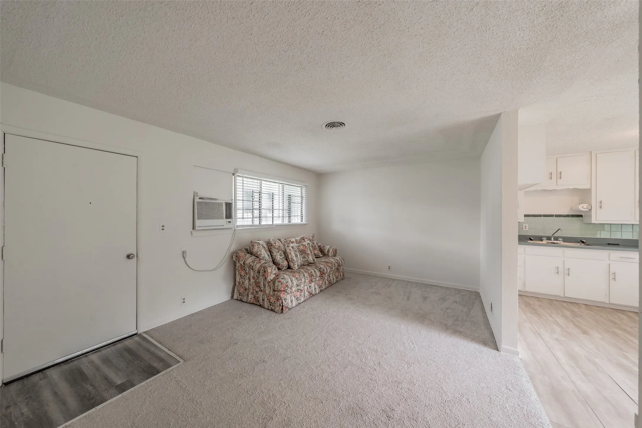 Living area featuring light carpet flooring and a window-mounted air conditioning unit