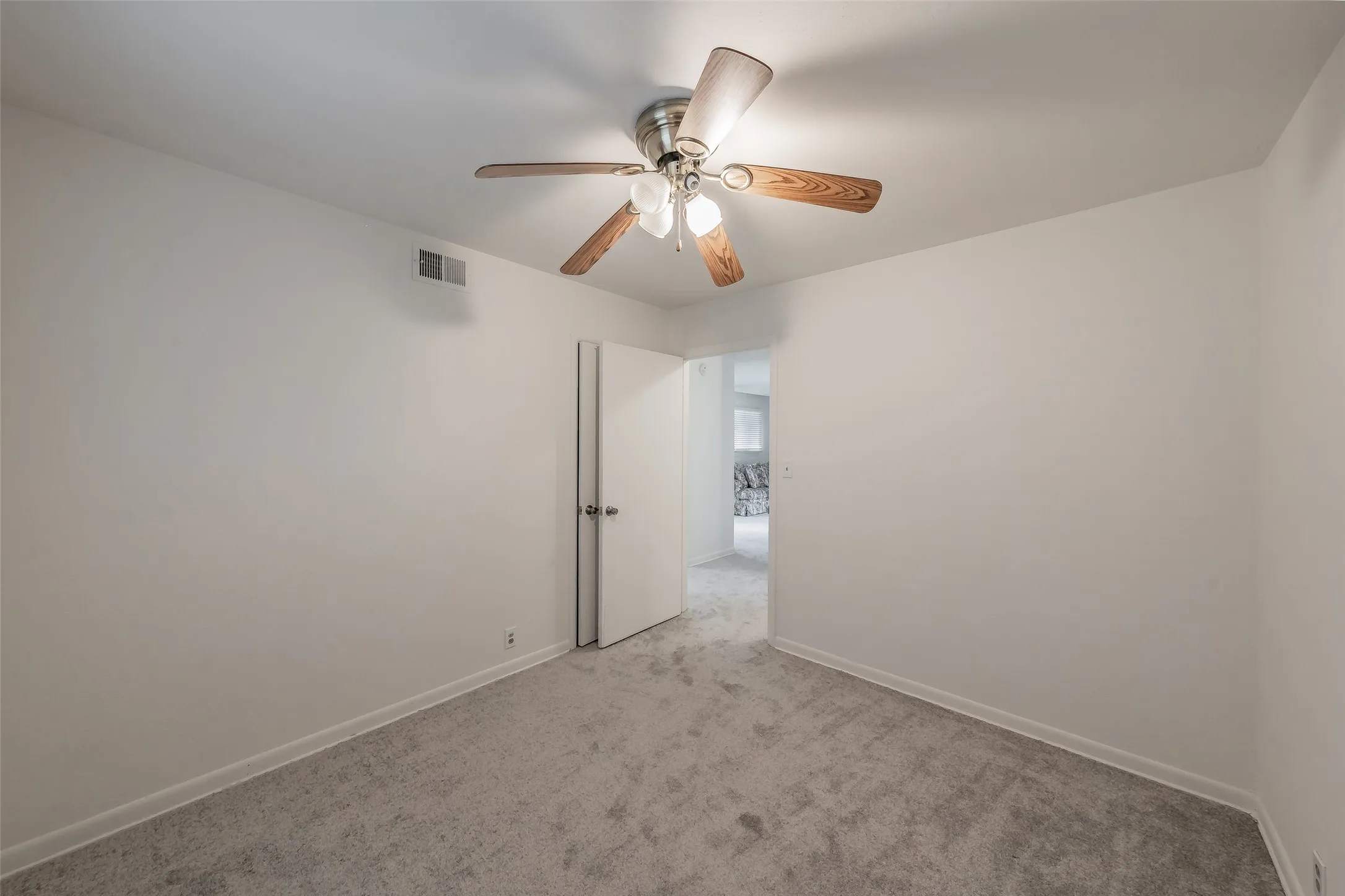 Bedroom 2Carpeted room featuring a ceiling fan with wood-finish blades, white walls, and a white interior door