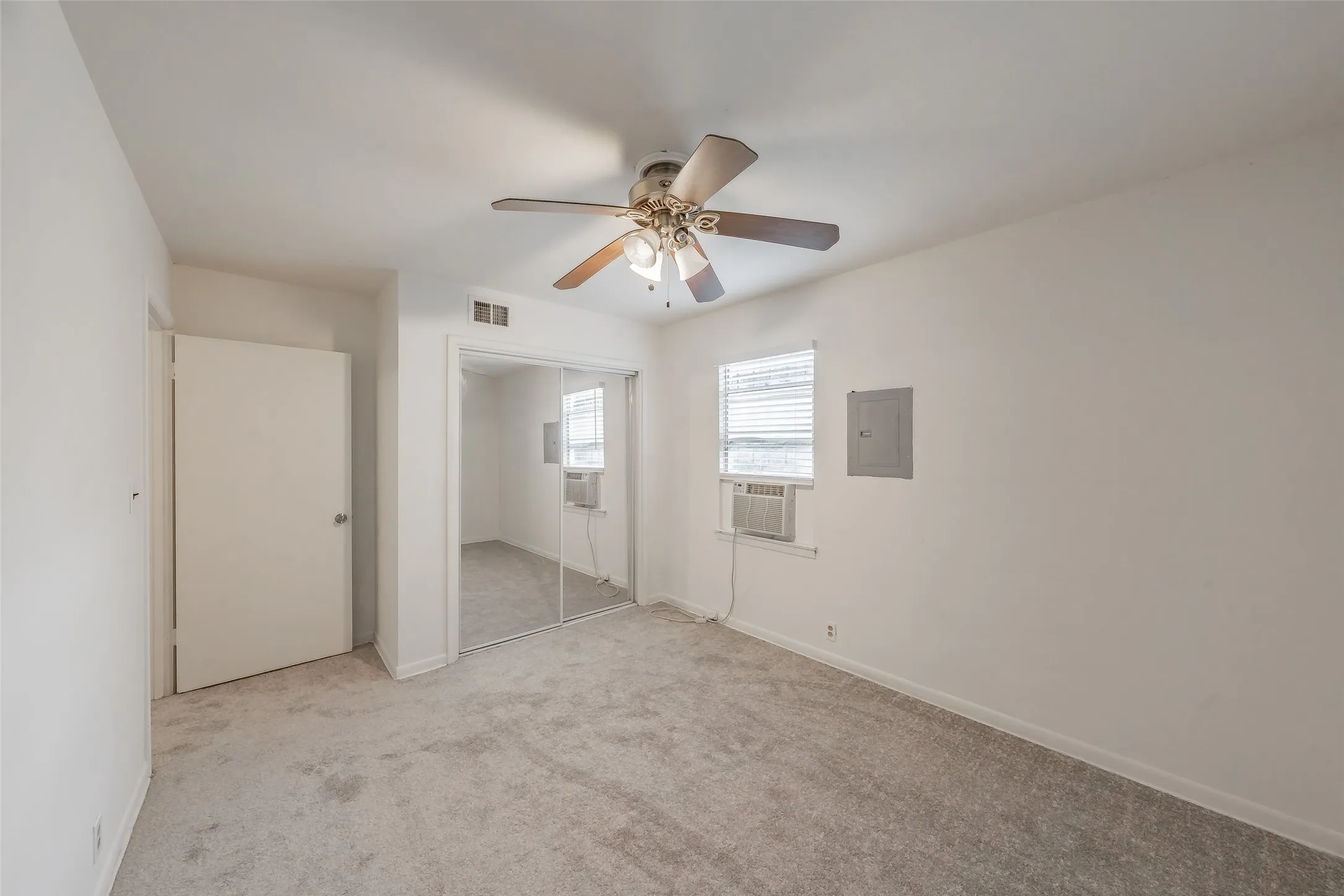 Bedroom 3 Carpeted interior room featuring a ceiling fan, mirrored closet doors, and window with blinds