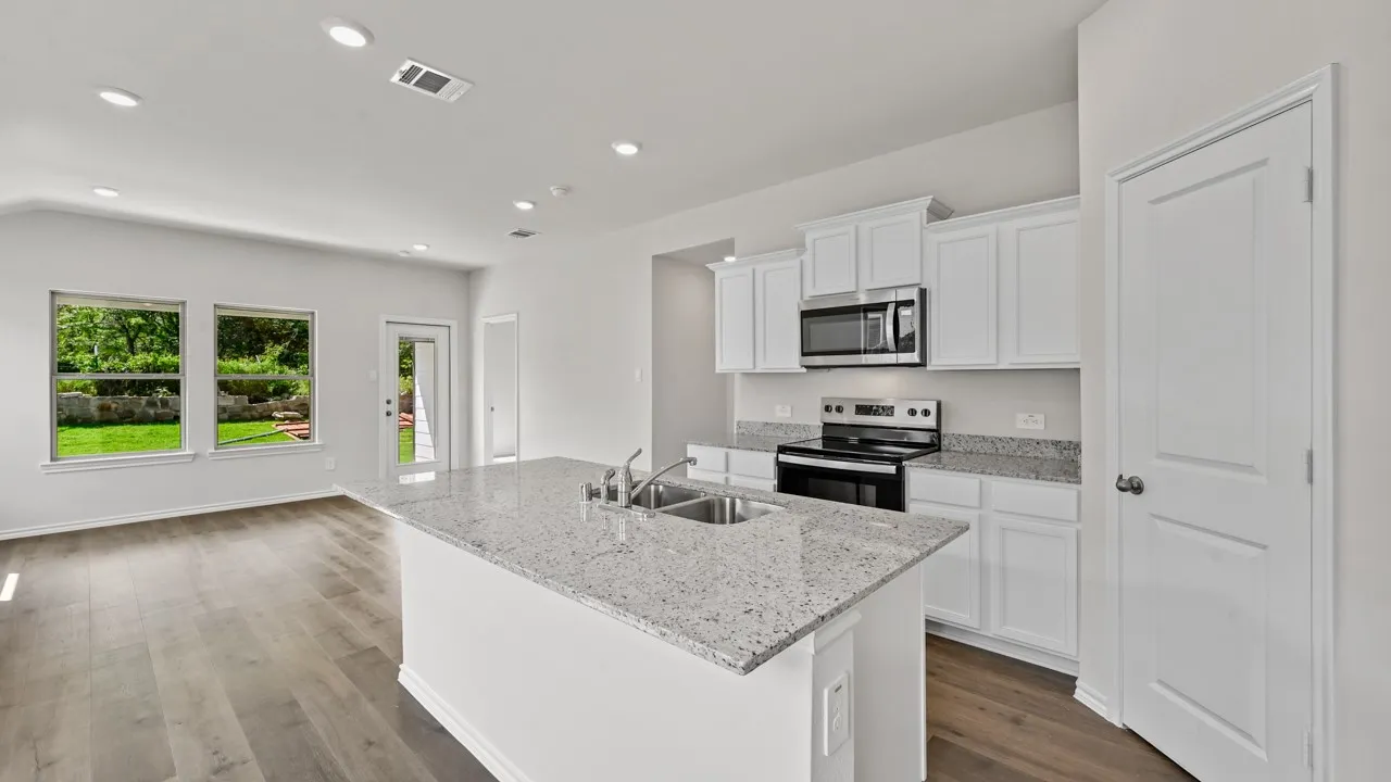 Modern kitchen featuring a central island with an undermount dual-basin sink and a speckled countertop